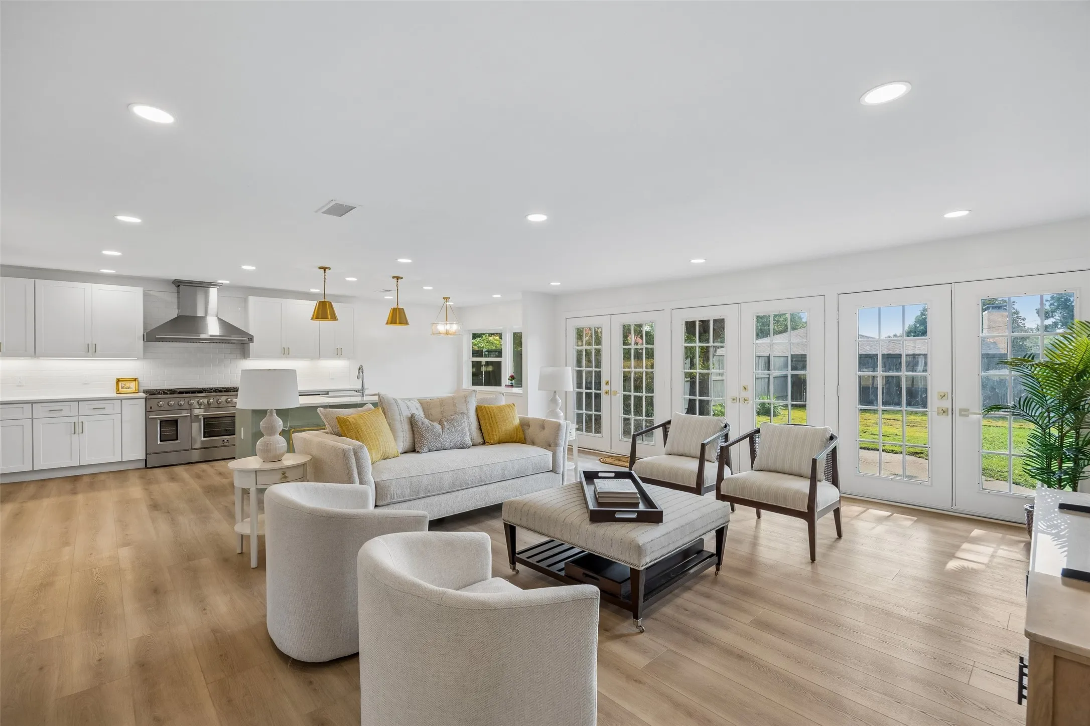 Open-concept living area with wood floors, abundant natural light and seamless flow into the kitchen and dining spaces.