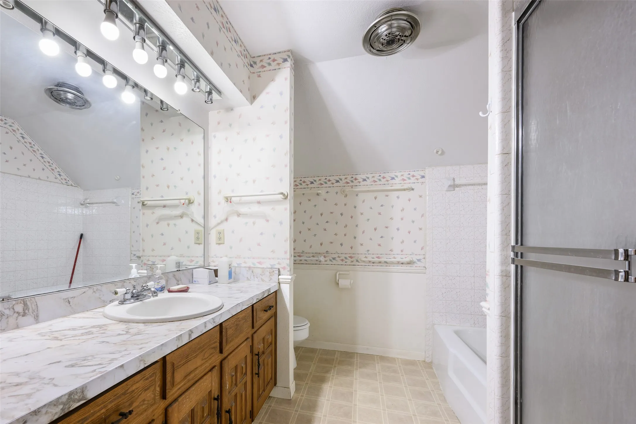 Vanity with a single basin sink, laminate countertop, and wood-finish cabinetry
