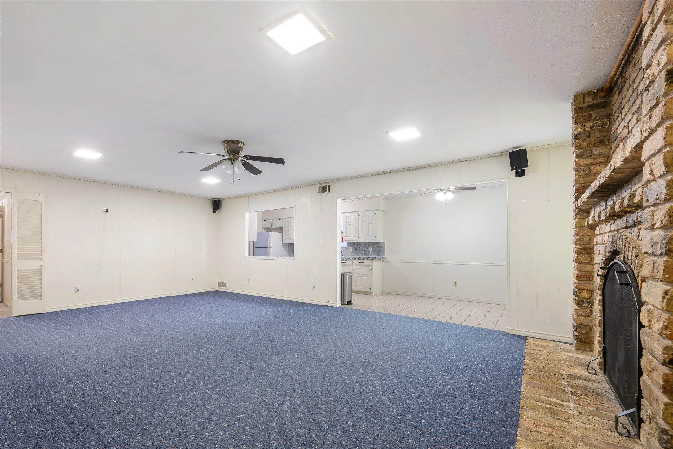 Spacious living area featuring a brick fireplace, ceiling fan, and recessed lighting