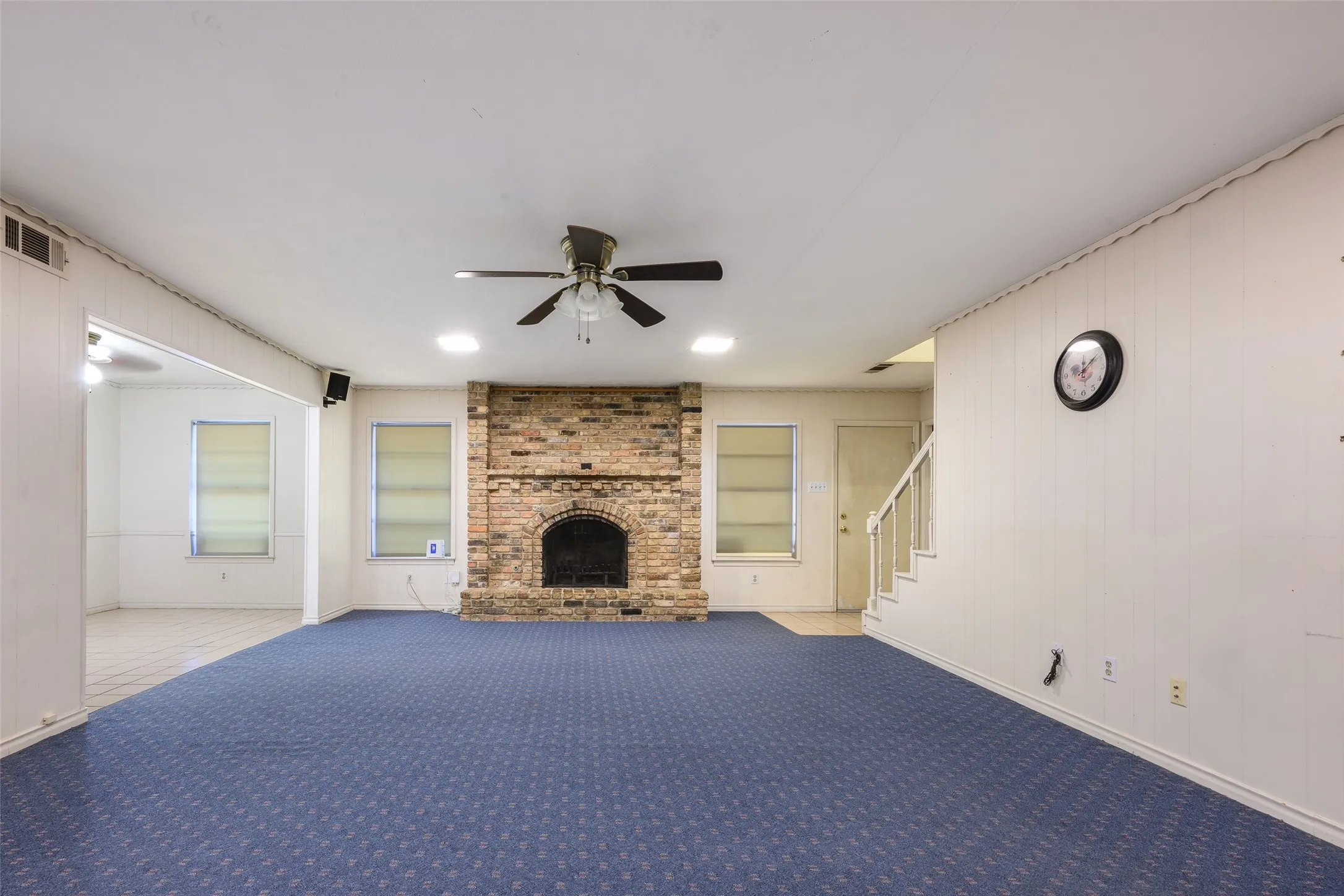 Brick fireplace with an arched opening, recessed lighting, ceiling fan, and carpeted flooring