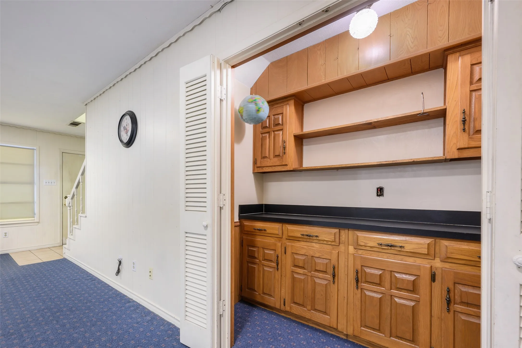 Built-in cabinetry with wood-finish doors and hardware, dark countertops, and open shelving