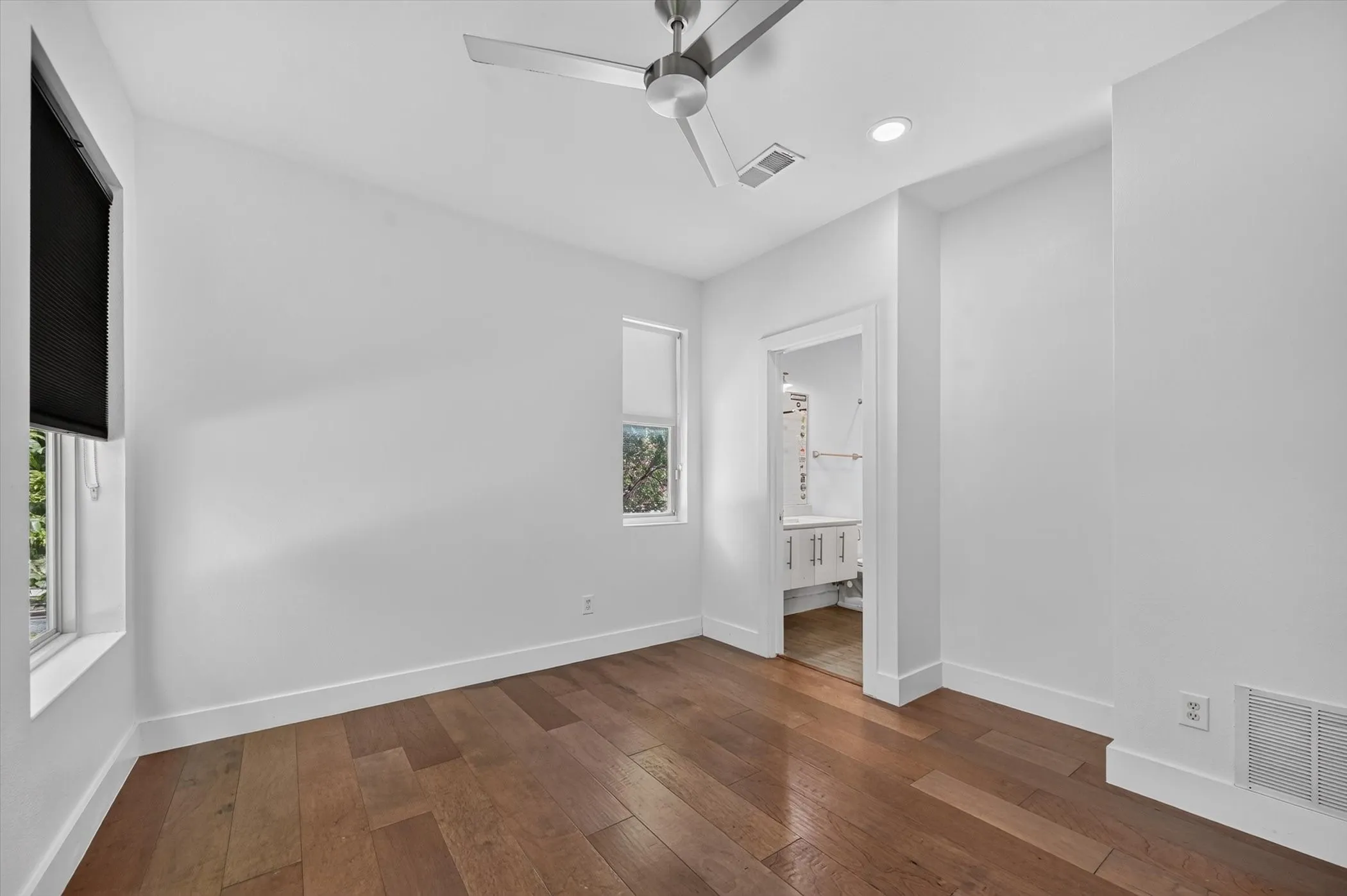 Hardwood flooring, recessed lighting, modern ceiling fan, and two windows with blinds