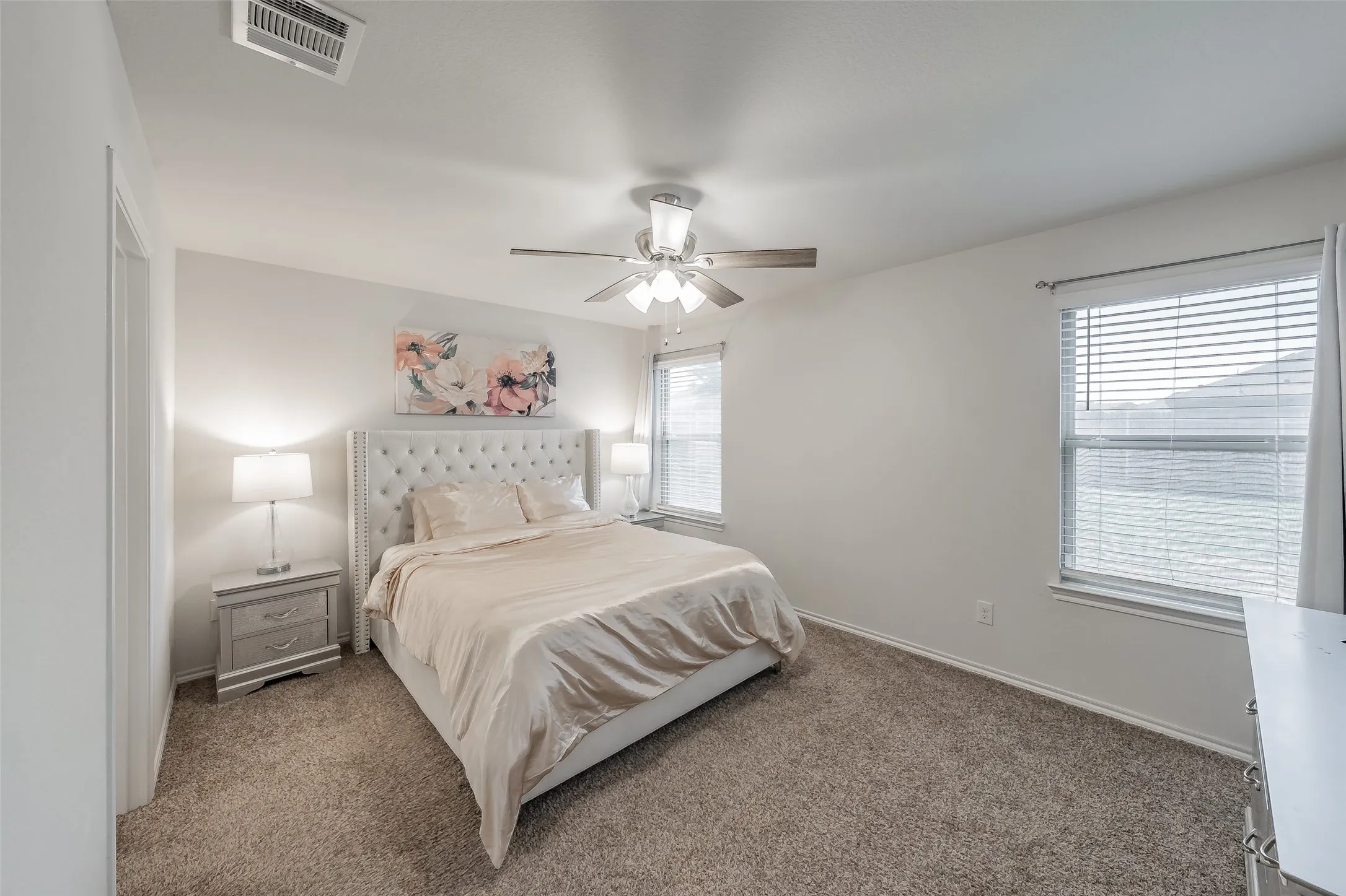 Plush carpet flooring, ceiling fan, and multiple windows with blinds