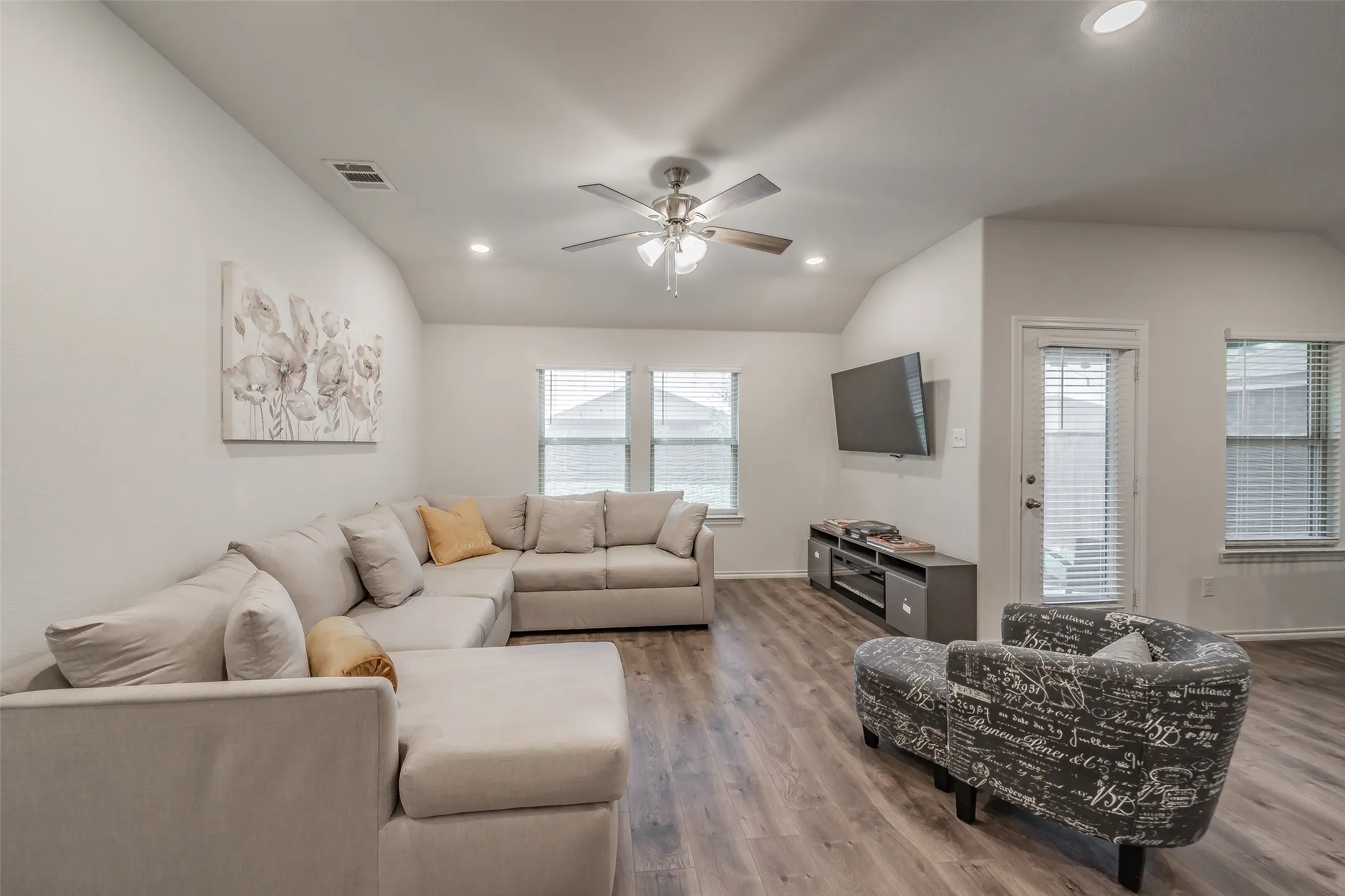 Vaulted ceiling with recessed lighting and a ceiling fan, wood-finish flooring, and multiple windows with blinds