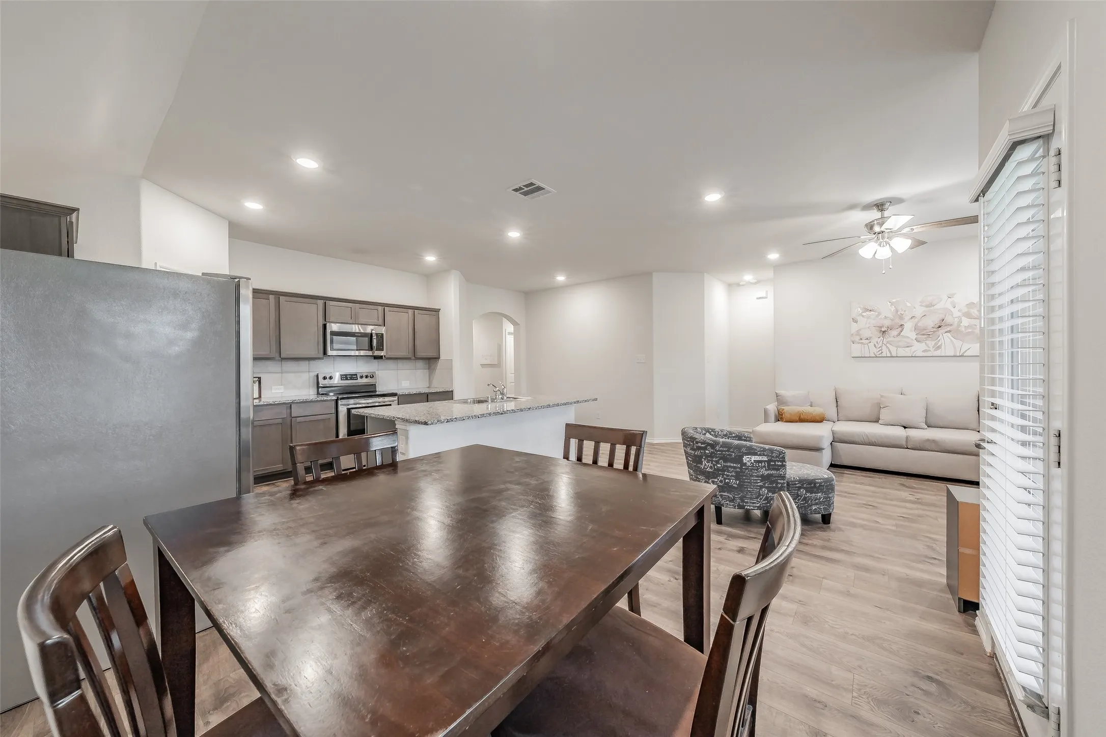Open-concept living space featuring wood-finish flooring, recessed lighting, and a ceiling fan