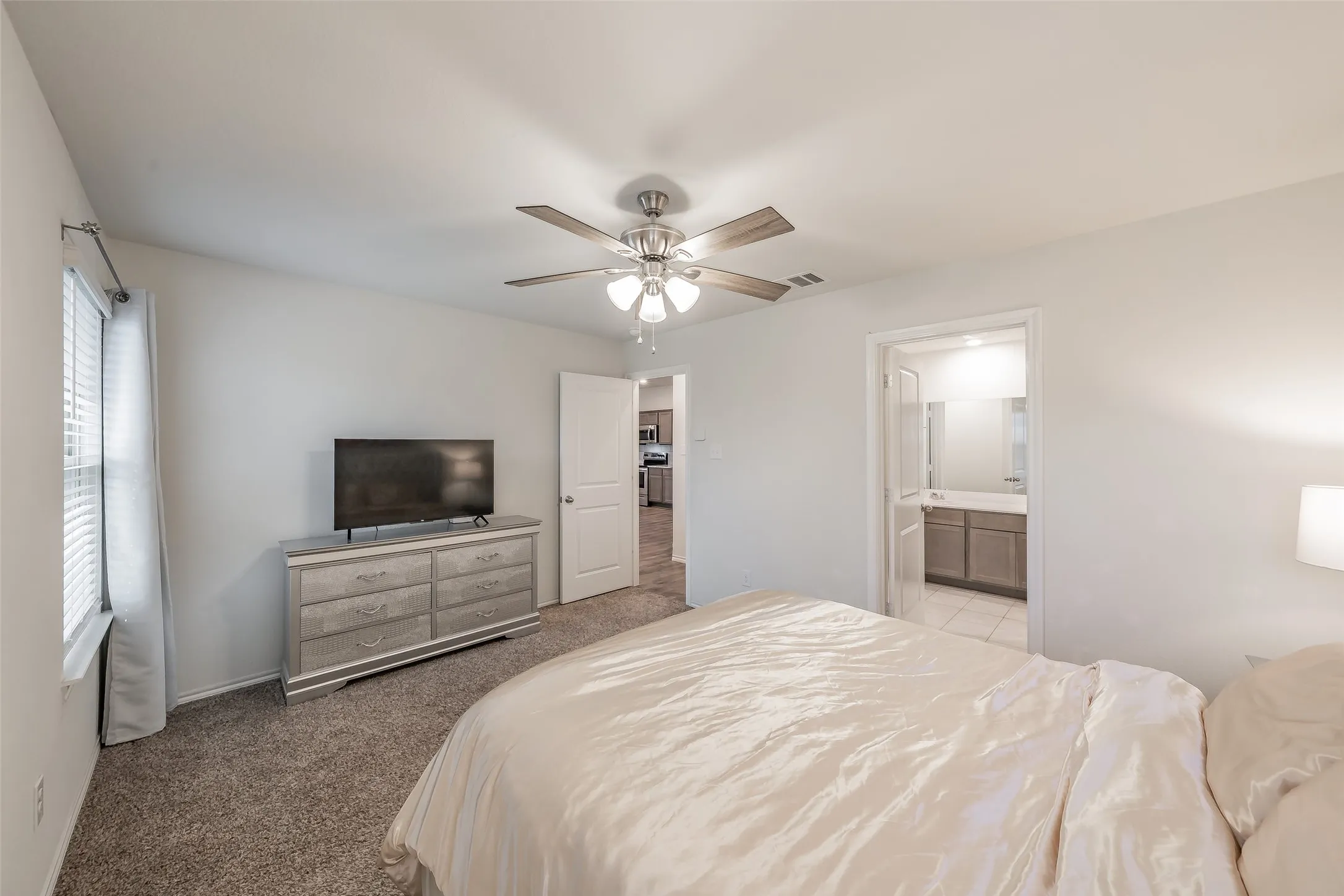 Carpeted room featuring a ceiling fan with light fixture and a window with blinds