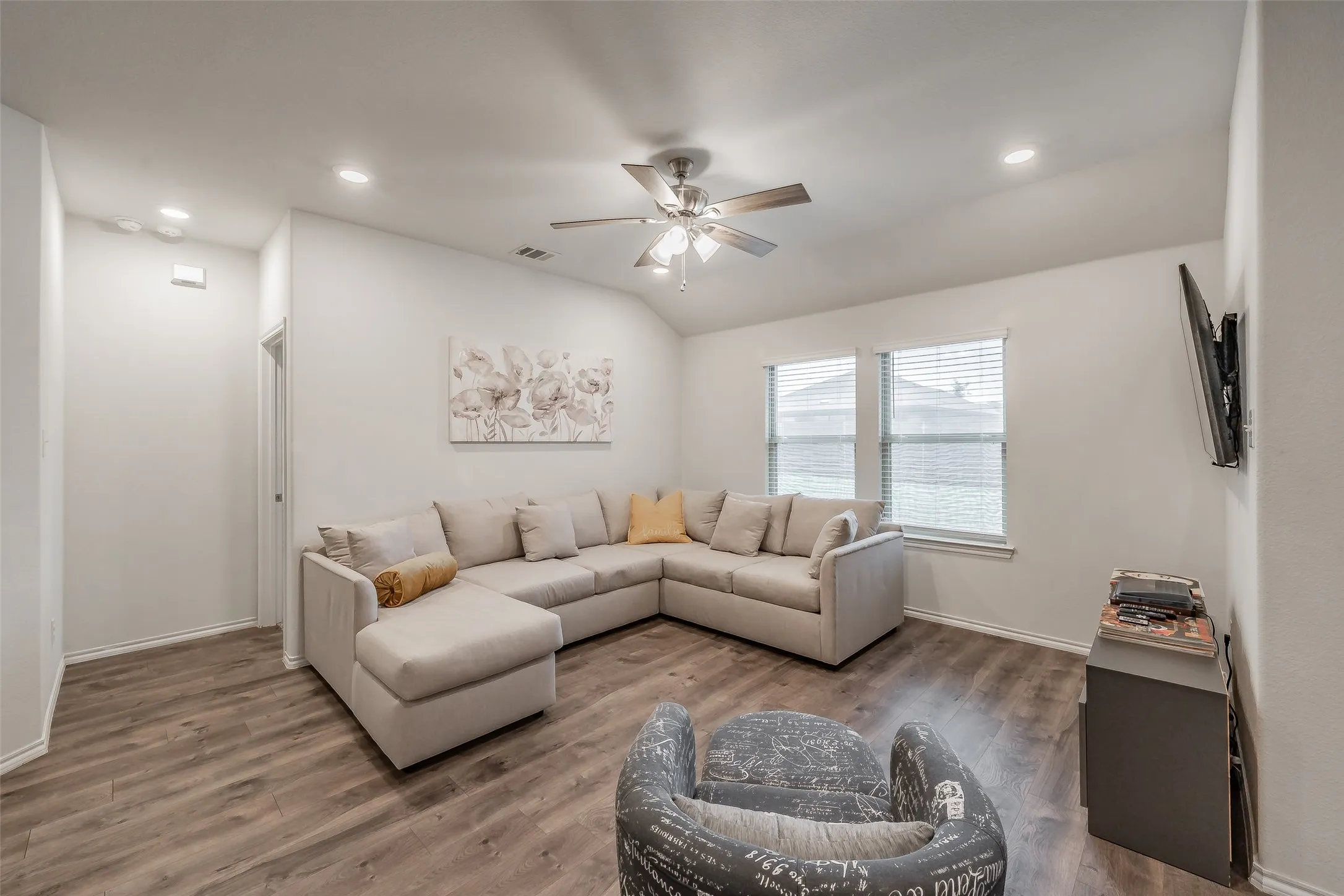 Vaulted ceiling with a ceiling fan, wood-finish flooring, recessed lighting, and dual windows