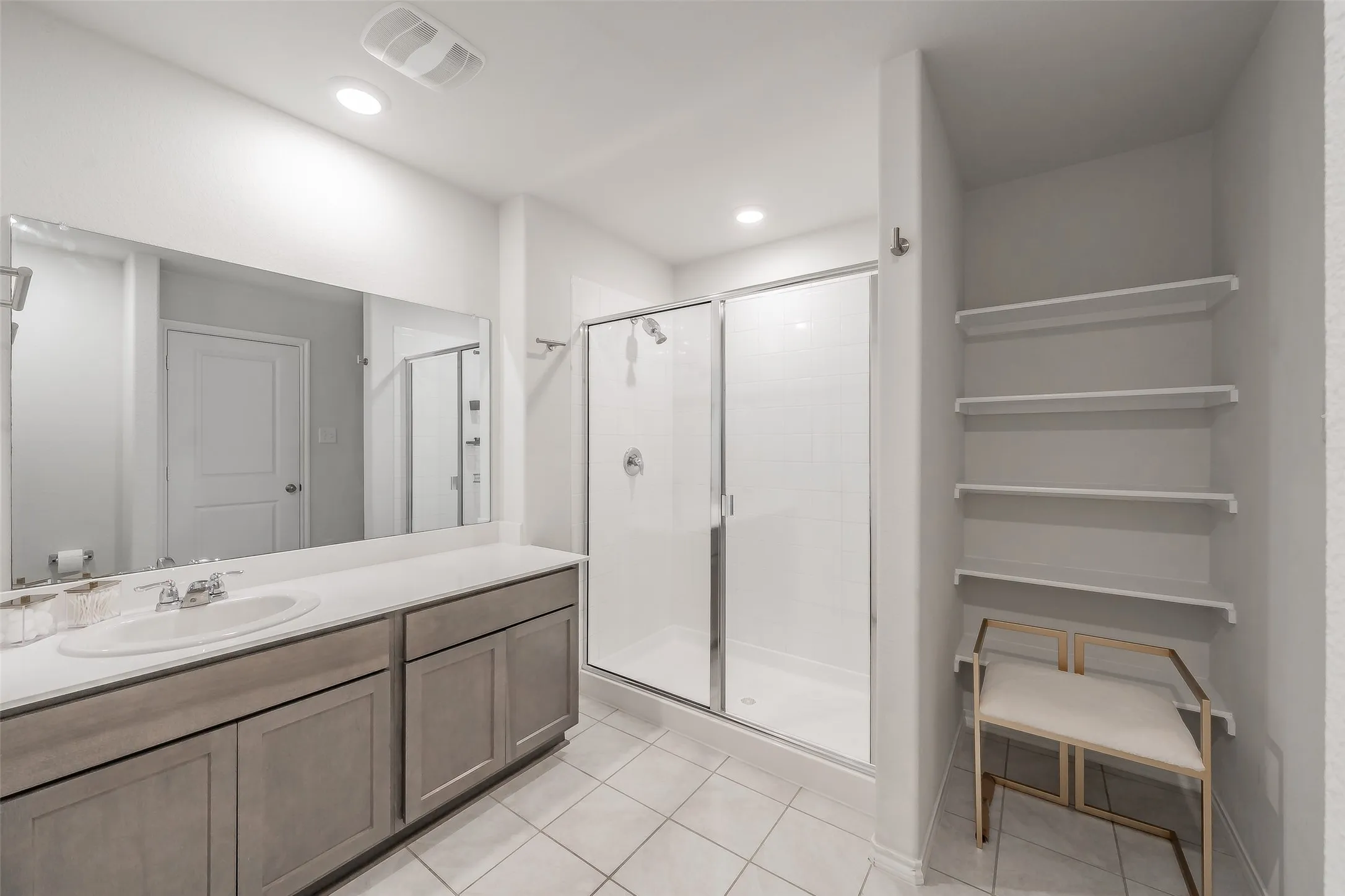 Dual vanity with undermount sinks, spacious mirror, and a walk-in shower with sliding glass doors