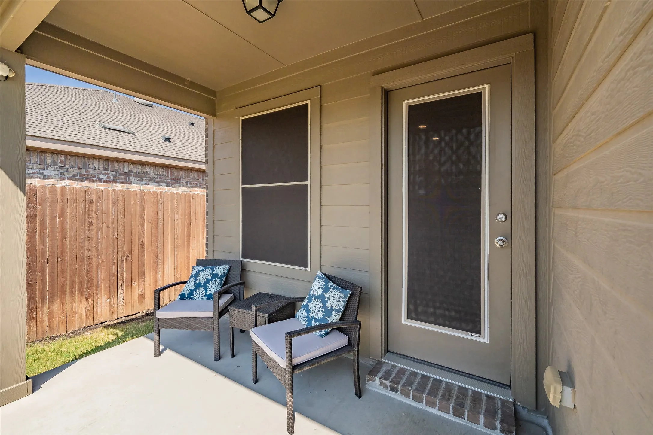 Covered patio with concrete flooring, wood privacy fence, and an exterior door with integrated screening