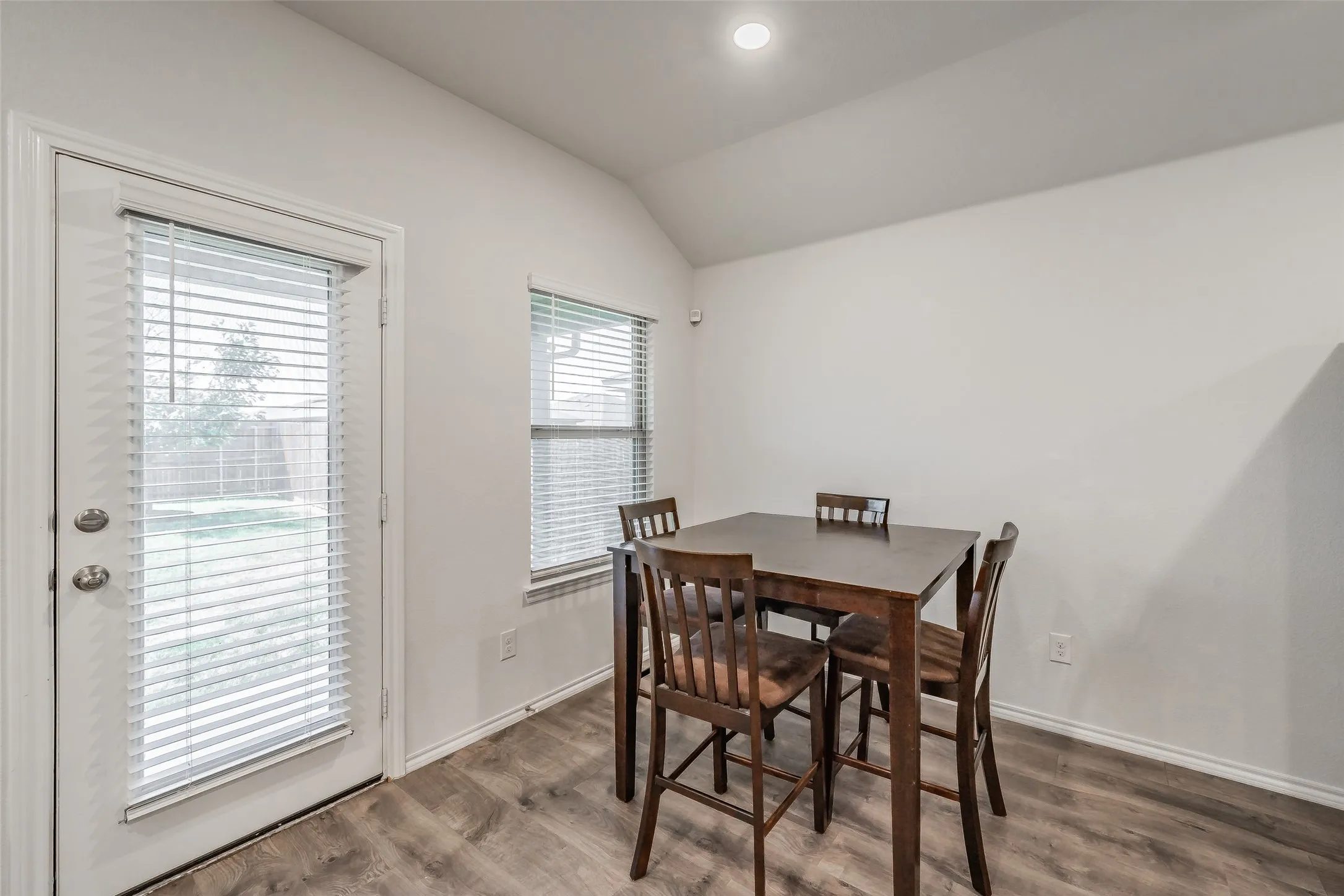Wood-finish flooring, white walls, and a vaulted ceiling