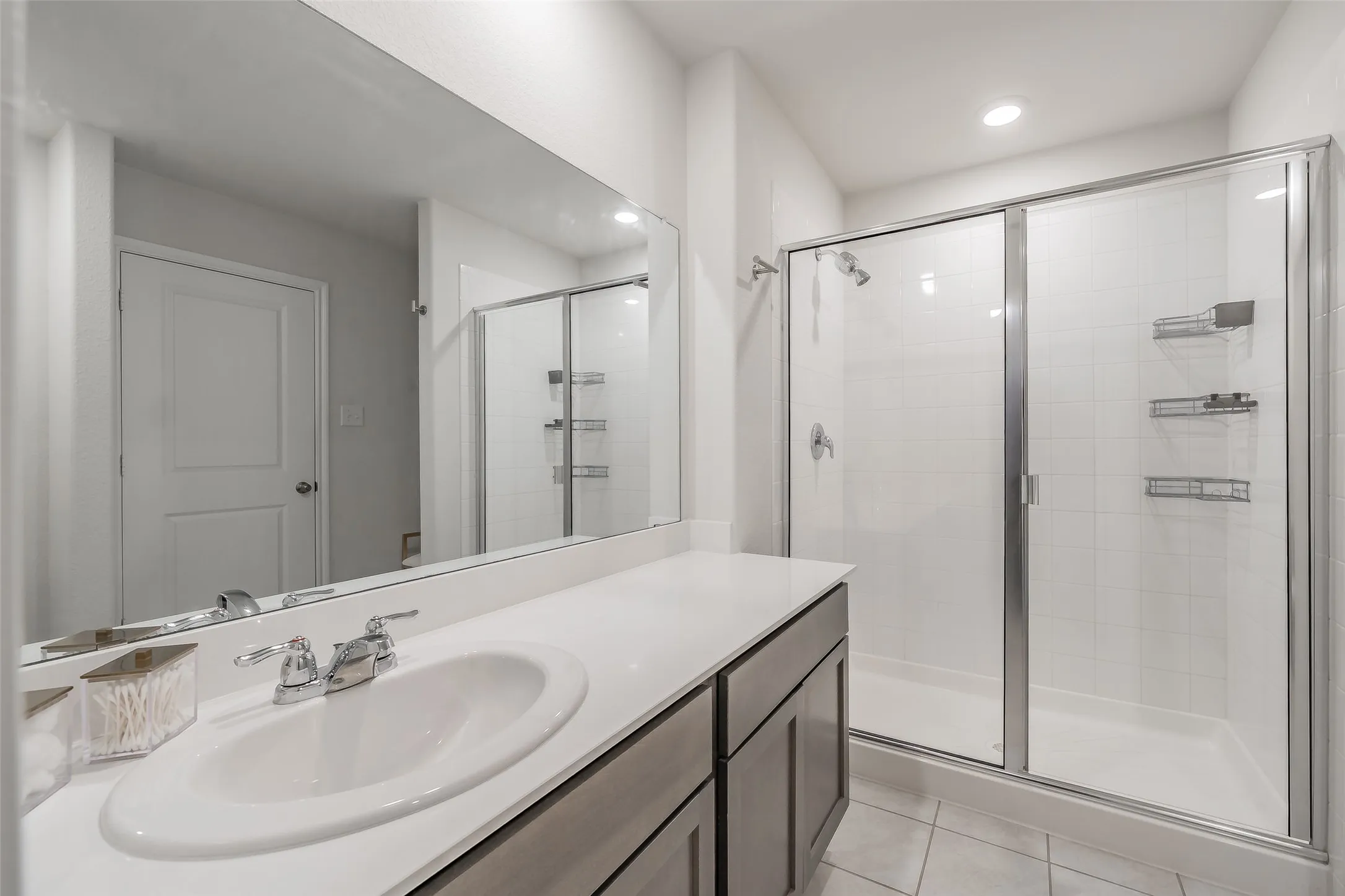 Bathroom featuring a single vanity with an integrated sink, polished chrome faucet, and a large frameless mirror