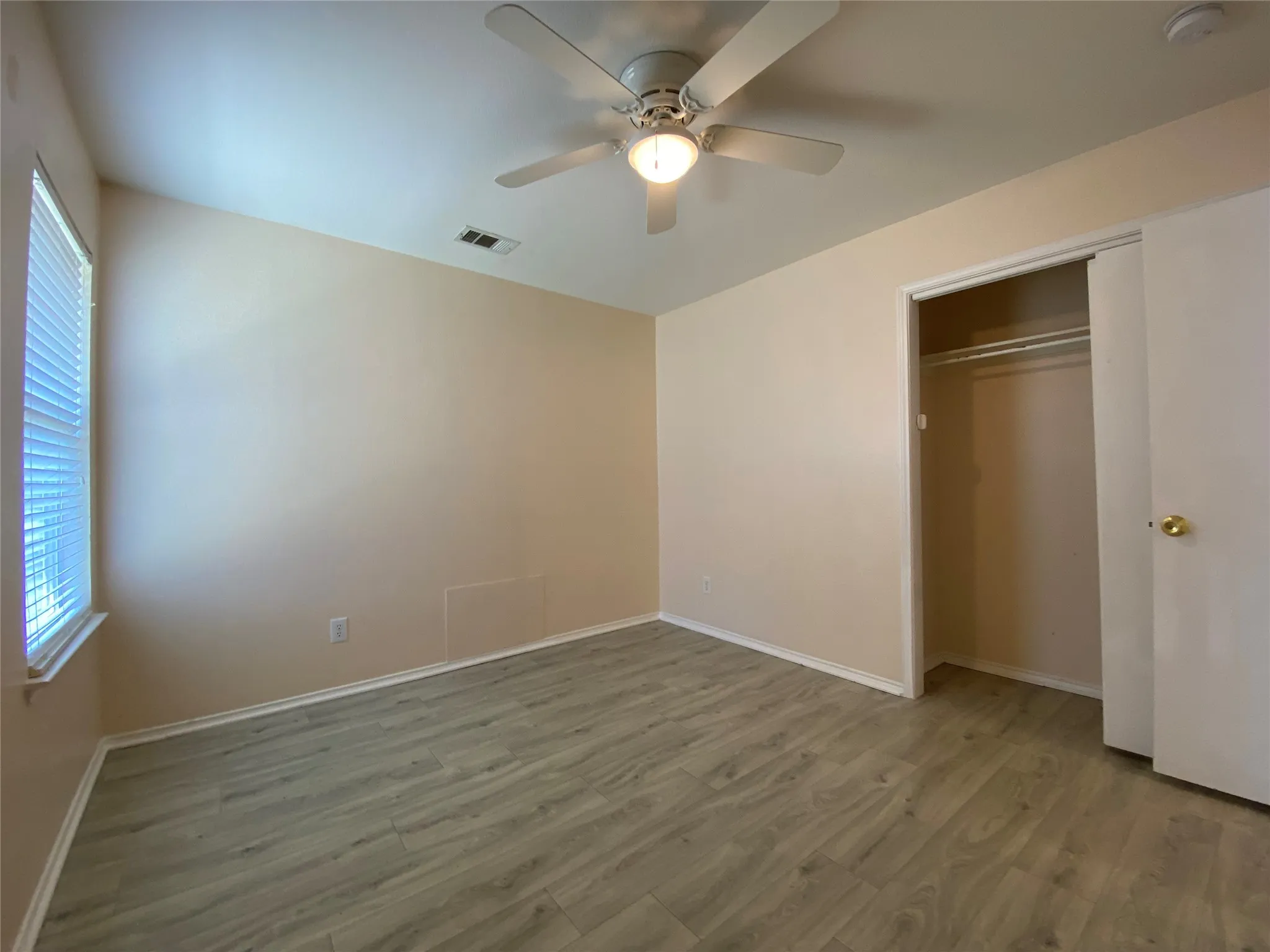 Unfurnished bedroom featuring wood finished floors, baseboards, a closet, and visible vents
