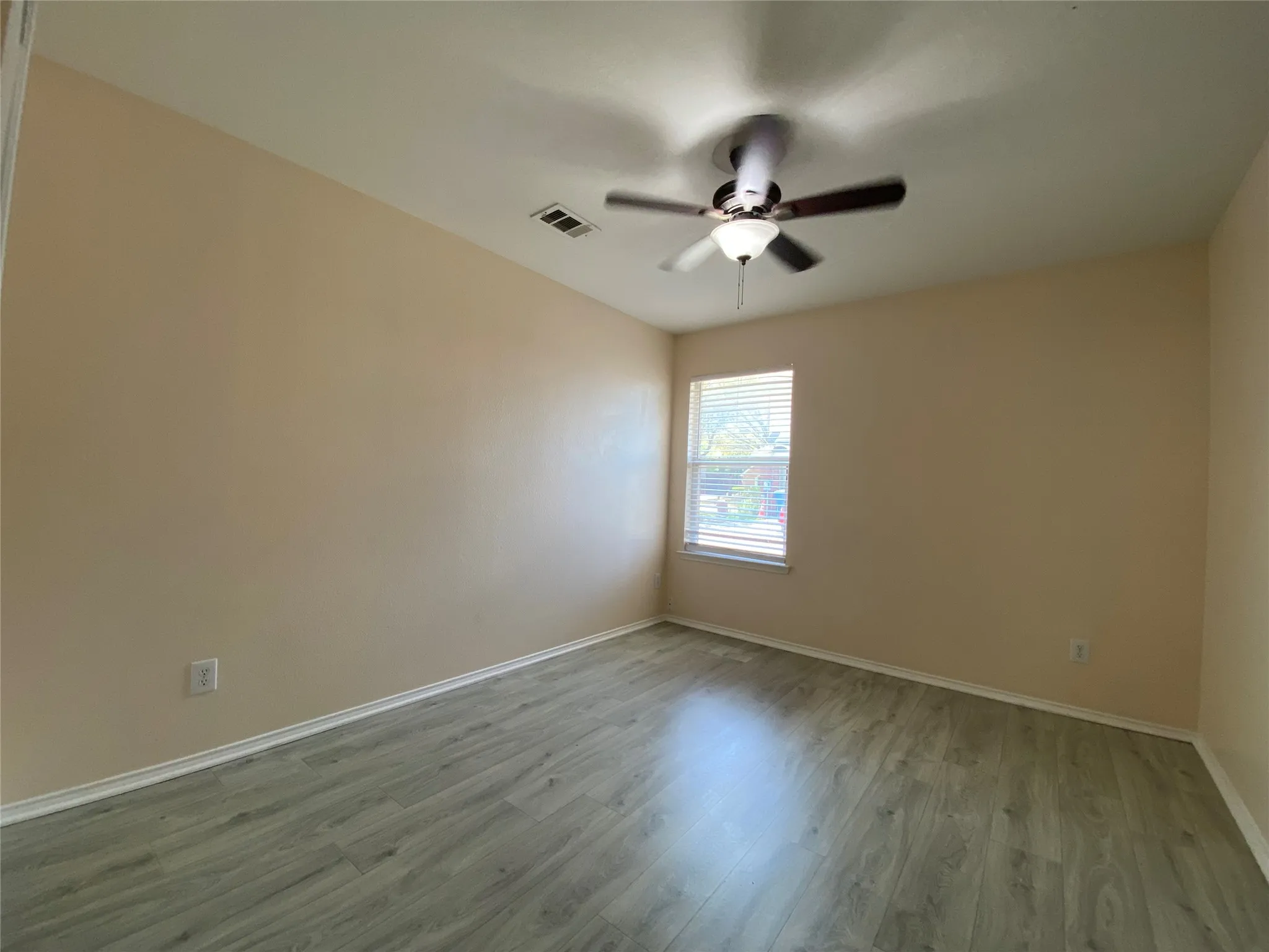 Spare room with baseboards, ceiling fan, visible vents, and wood finished floors