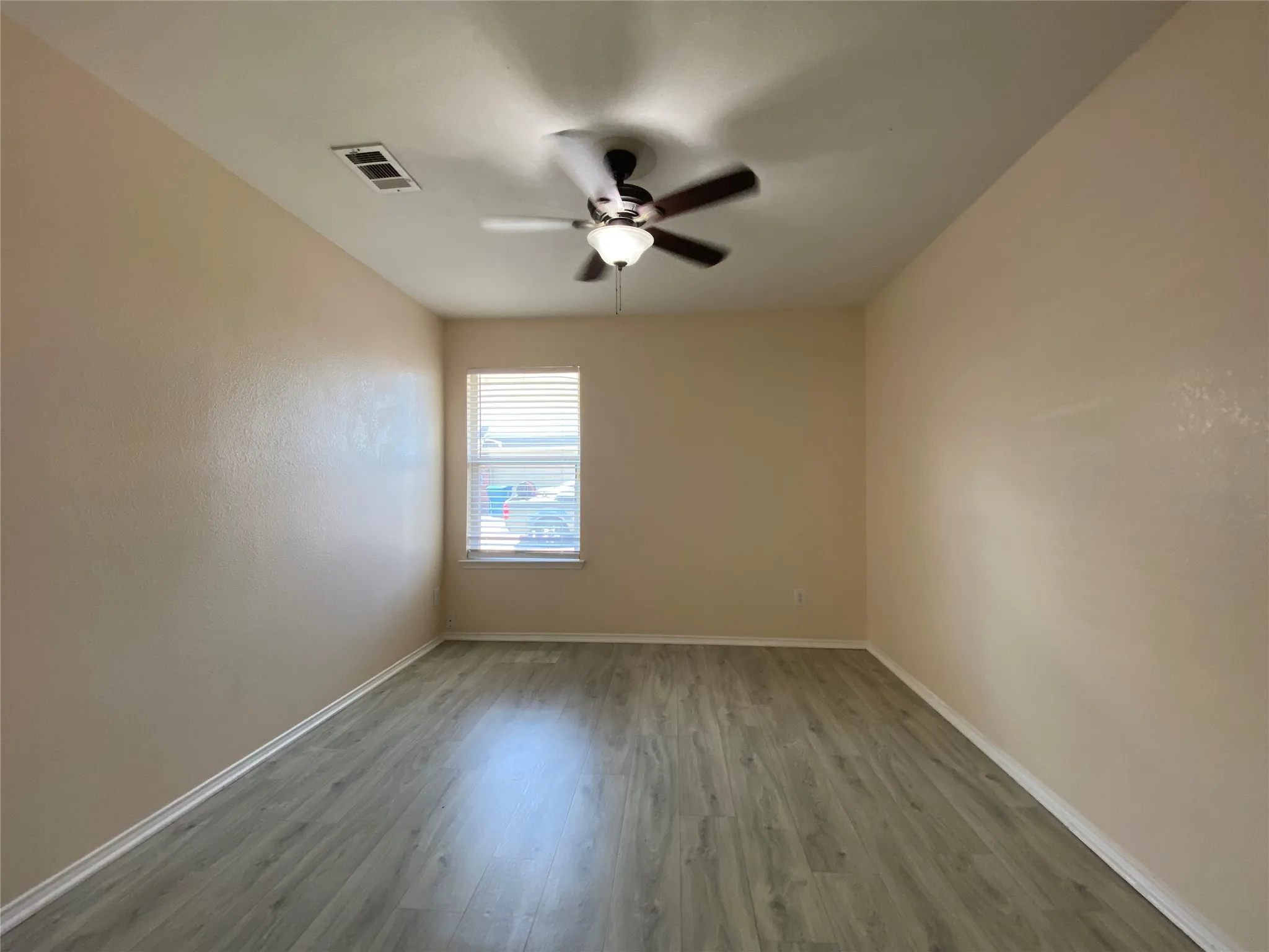 Spare room featuring a ceiling fan, wood finished floors, baseboards, and visible vents