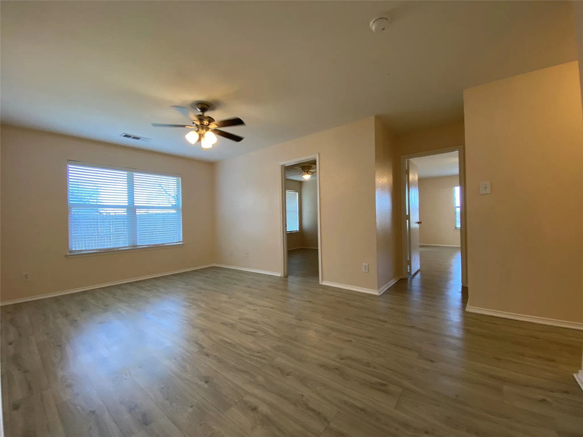 Unfurnished room with dark wood finished floors, baseboards, visible vents, and ceiling fan