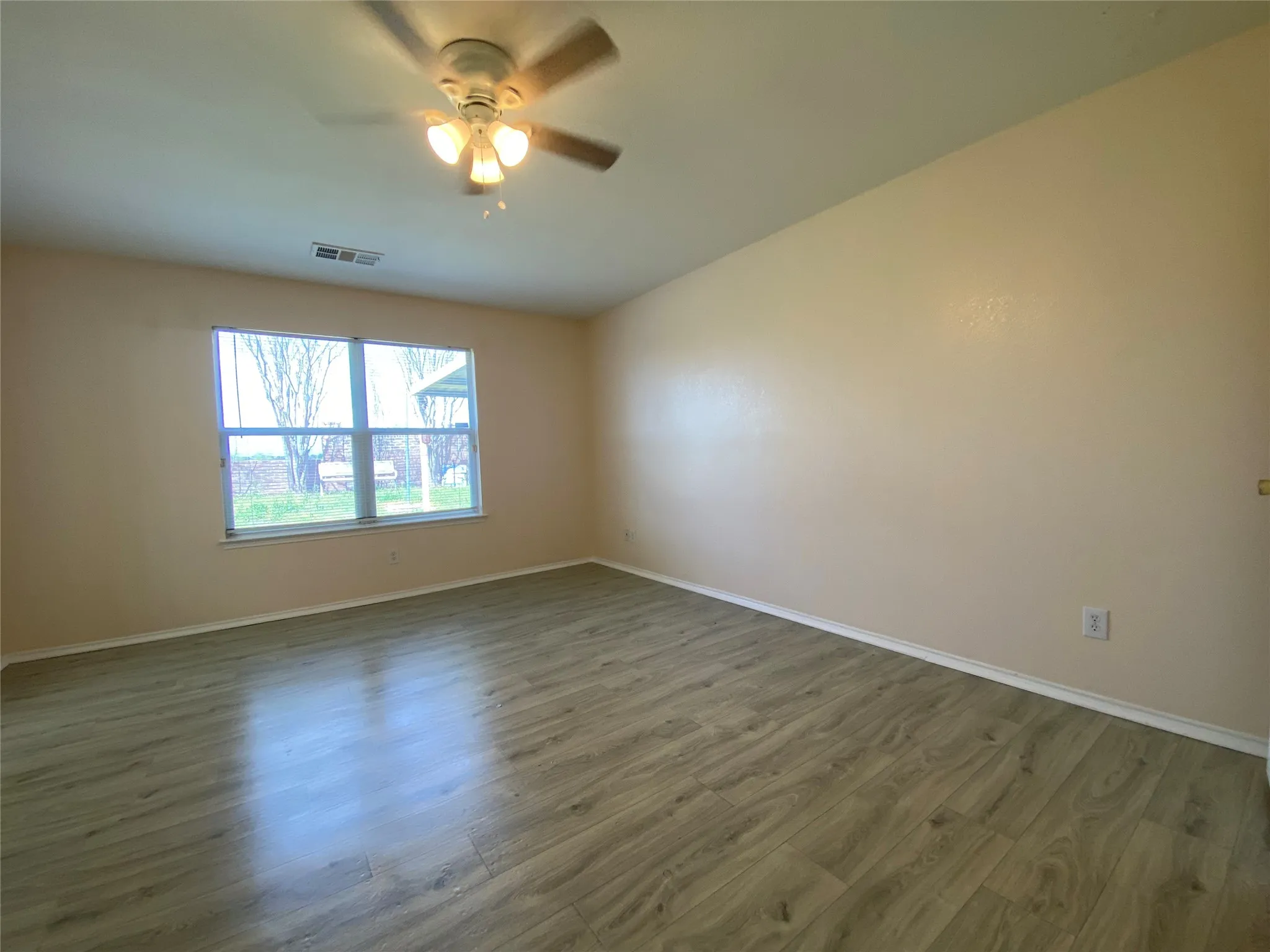 Unfurnished room featuring baseboards, dark wood-style flooring, ceiling fan, and visible vents