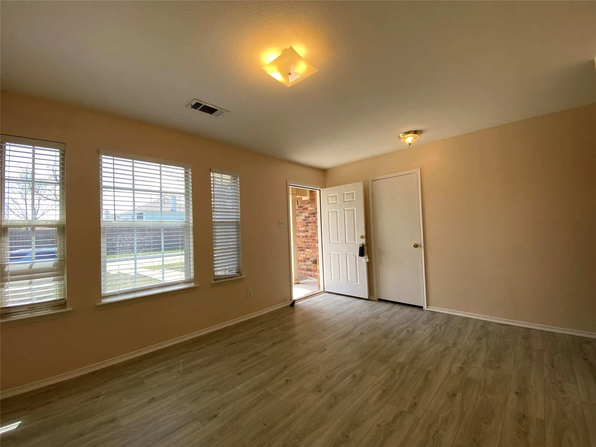 Empty room featuring wood finished floors, baseboards, and visible vents