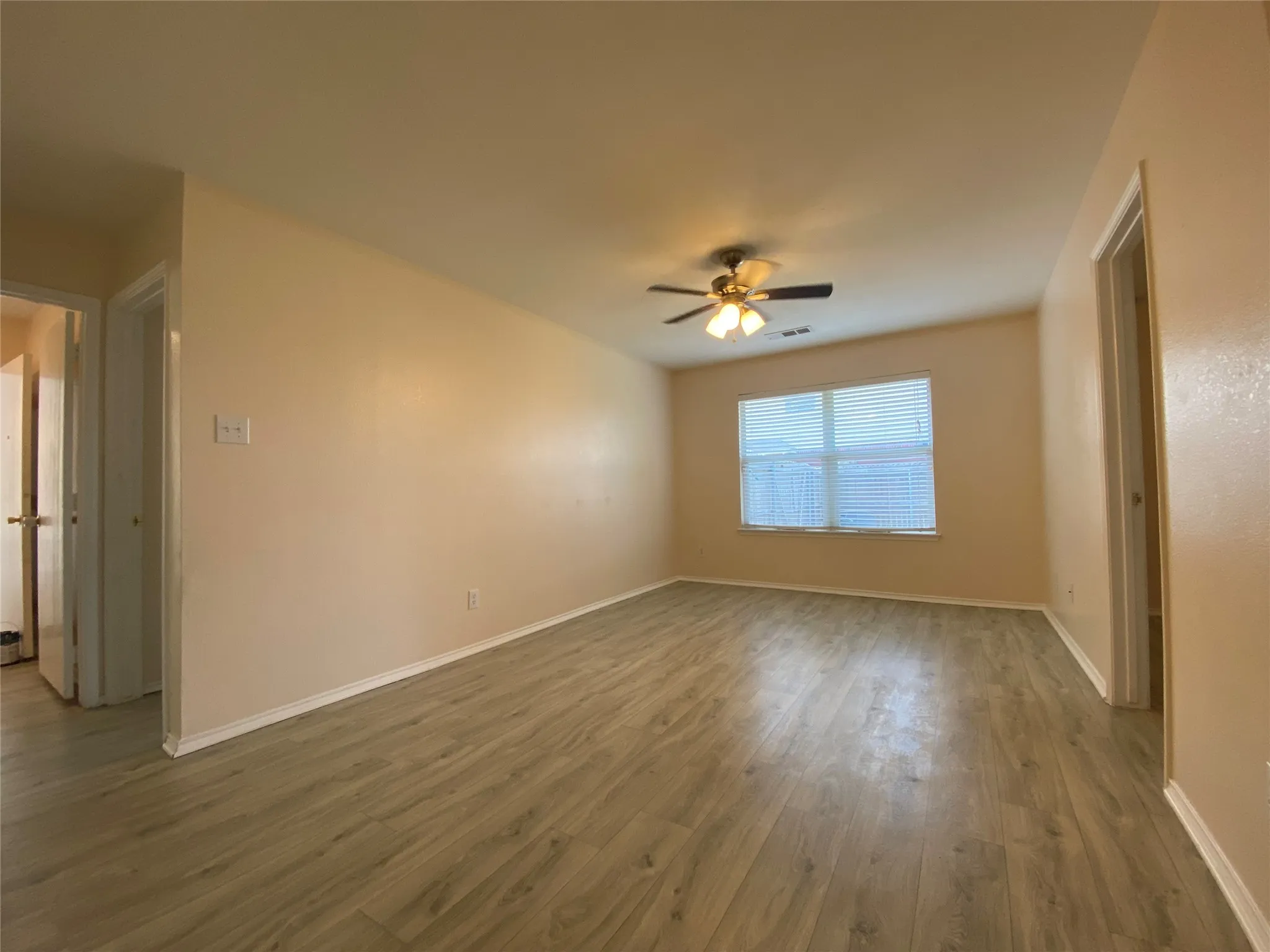 Spare room with baseboards, visible vents, a ceiling fan, and dark wood finished floors