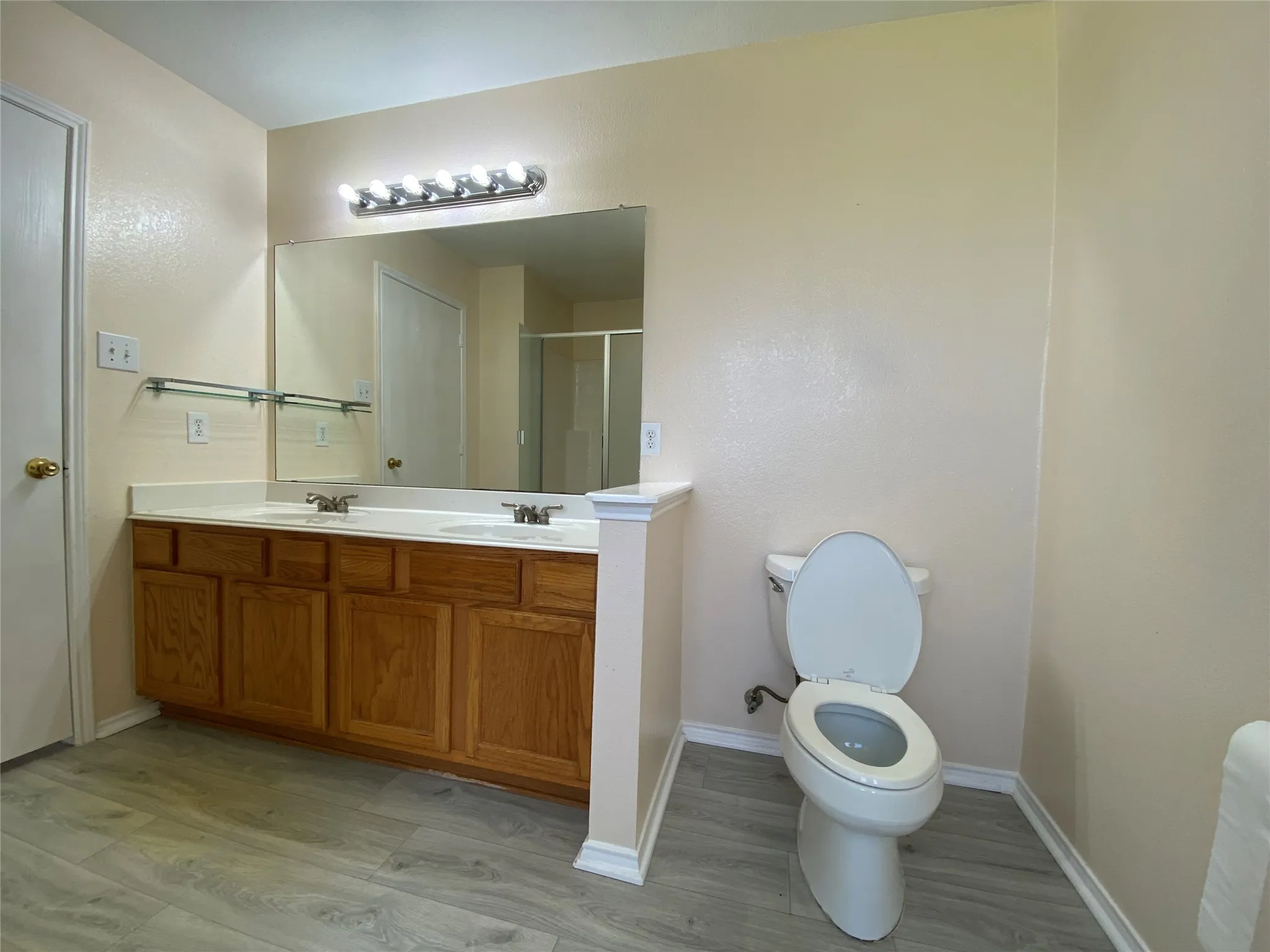 Bathroom featuring toilet, a sink, a shower stall, baseboards, and double vanity