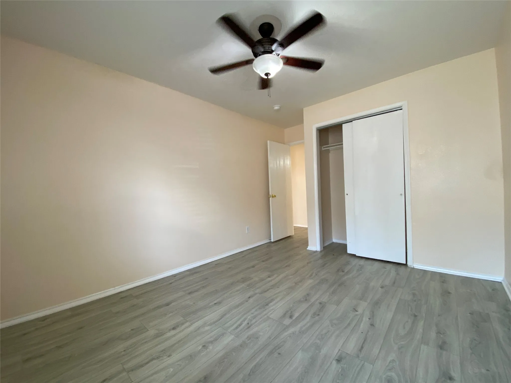 Unfurnished bedroom featuring a closet, baseboards, wood finished floors, and a ceiling fan