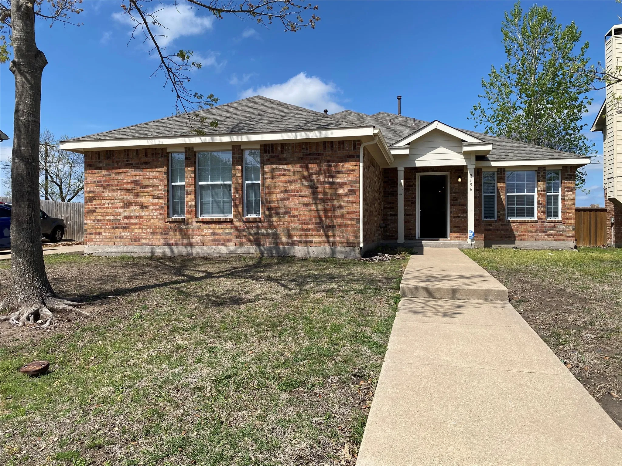 View of front of house with a front yard, fence, brick siding, and roof with shingles