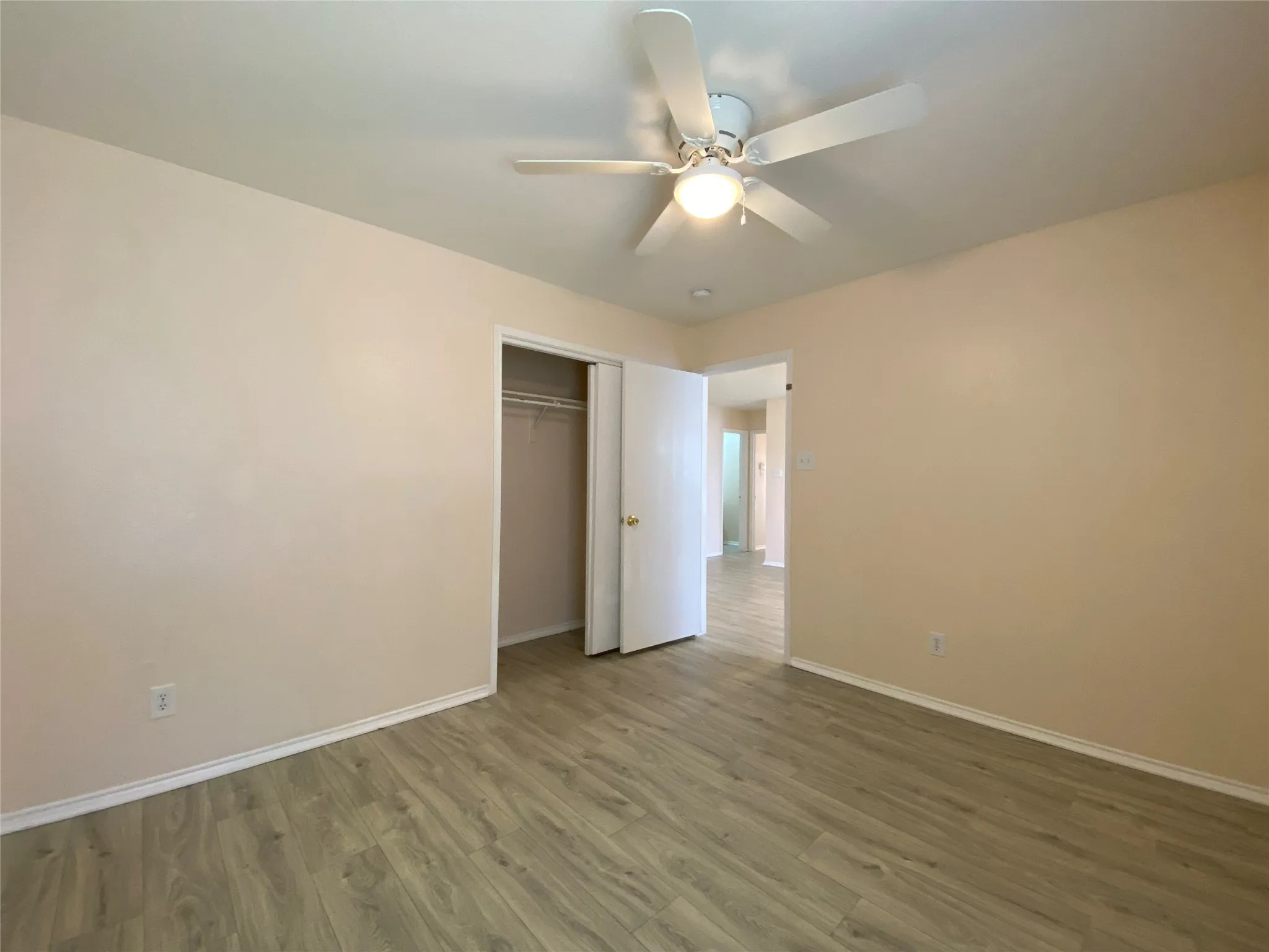 Unfurnished bedroom with a ceiling fan, baseboards, a closet, and wood finished floors