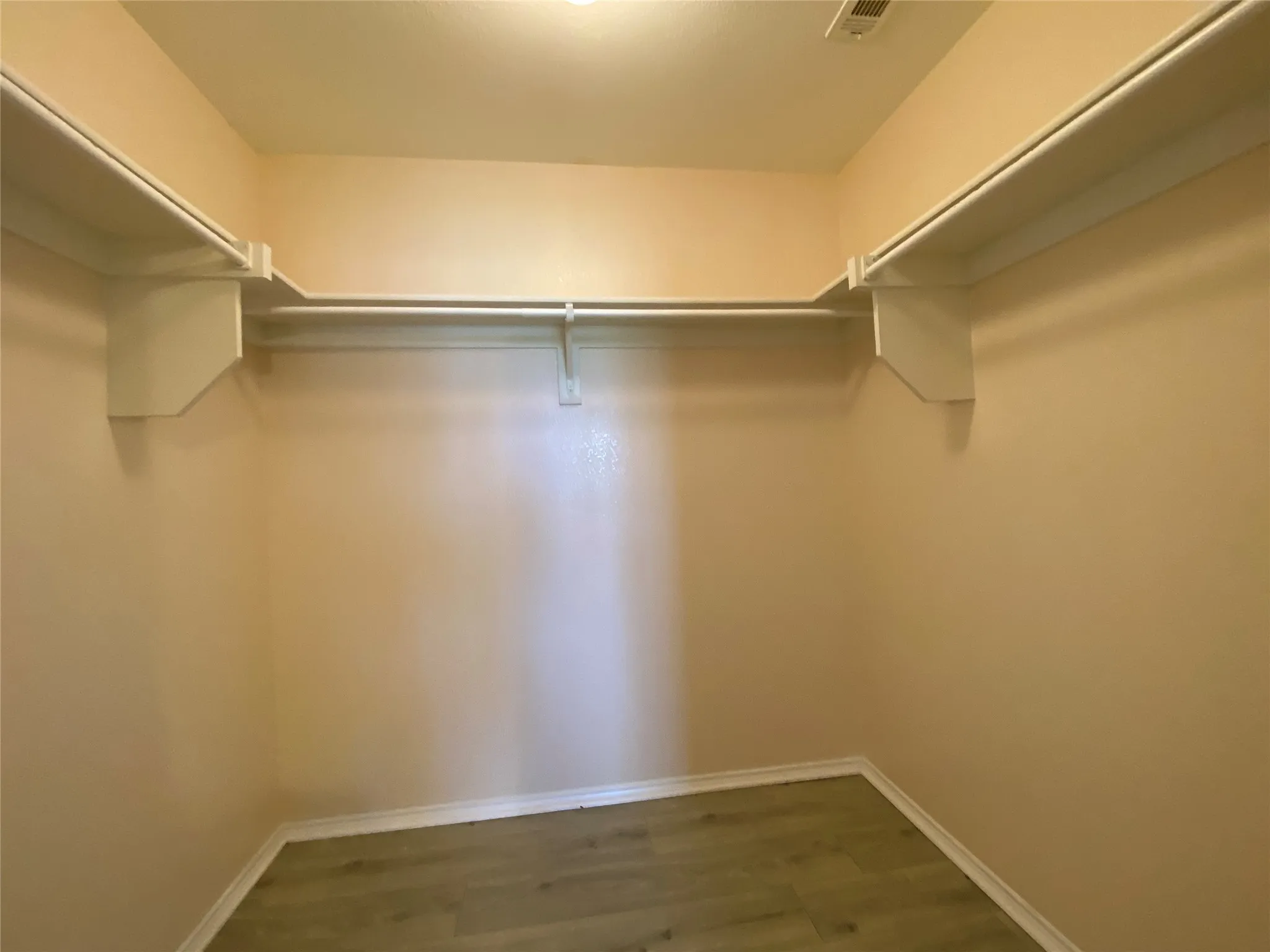 Walk in closet featuring visible vents and wood finished floors