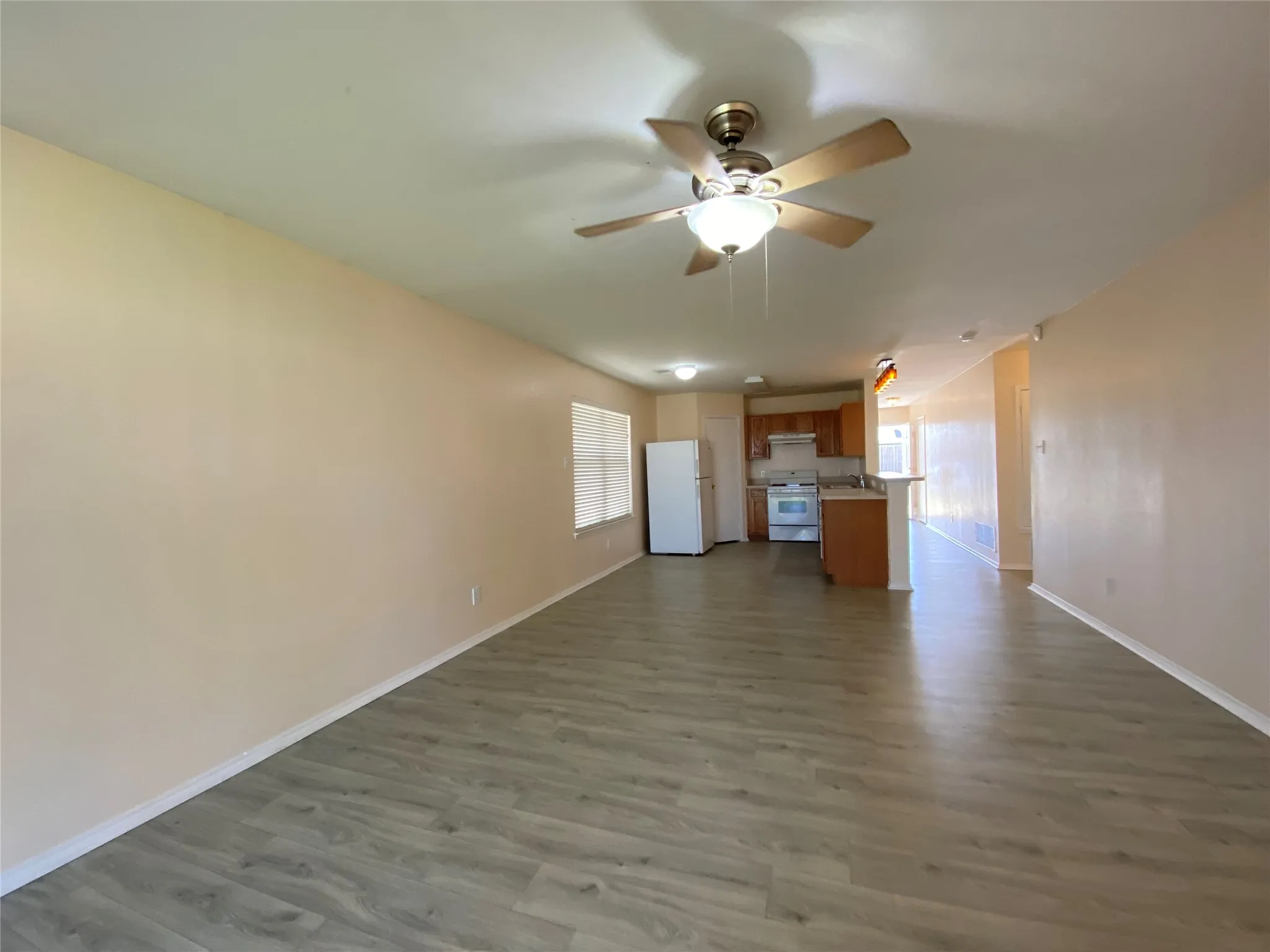 Unfurnished living room featuring dark wood finished floors, baseboards, and ceiling fan