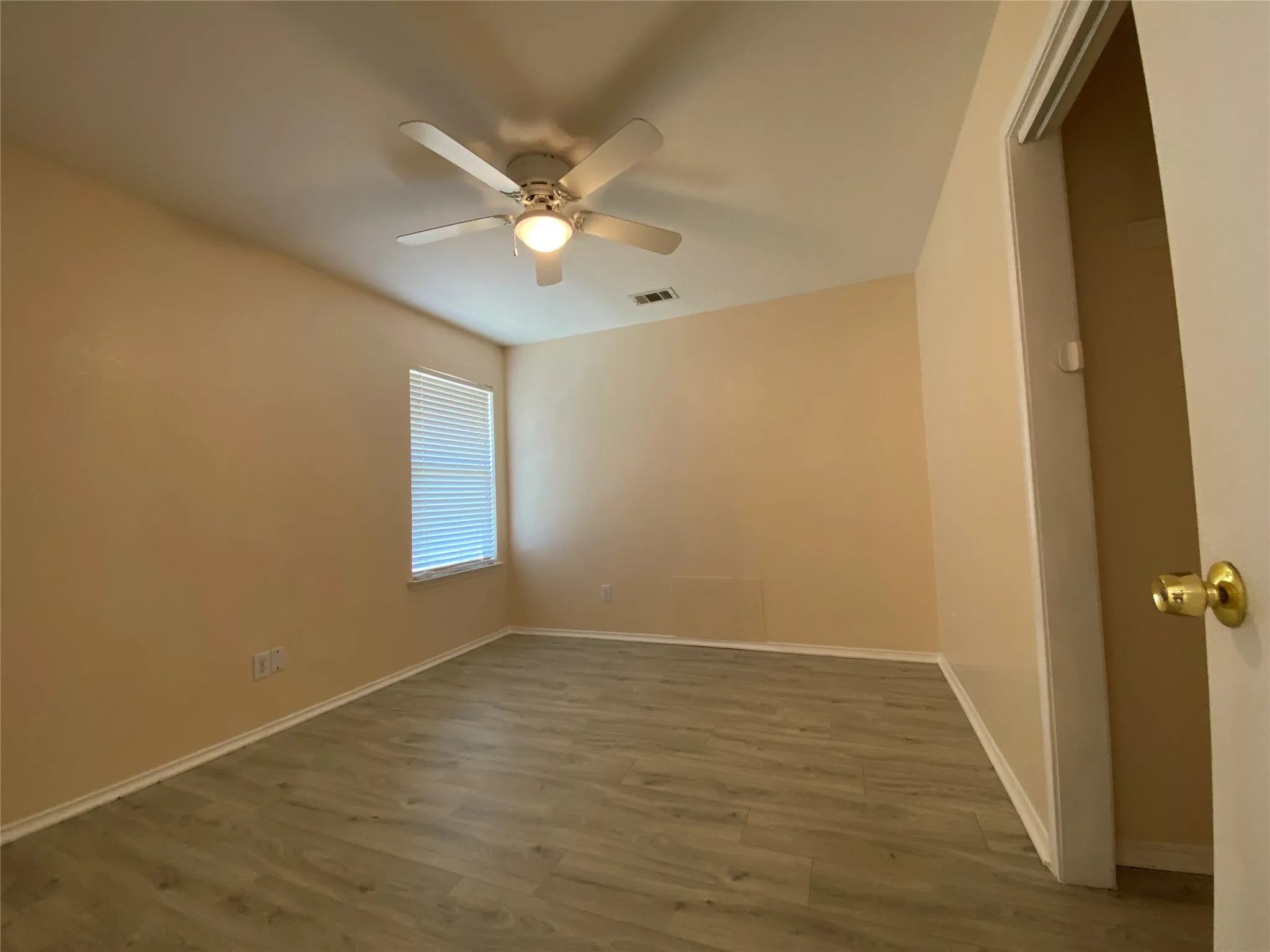 Unfurnished room with baseboards, visible vents, wood finished floors, and ceiling fan
