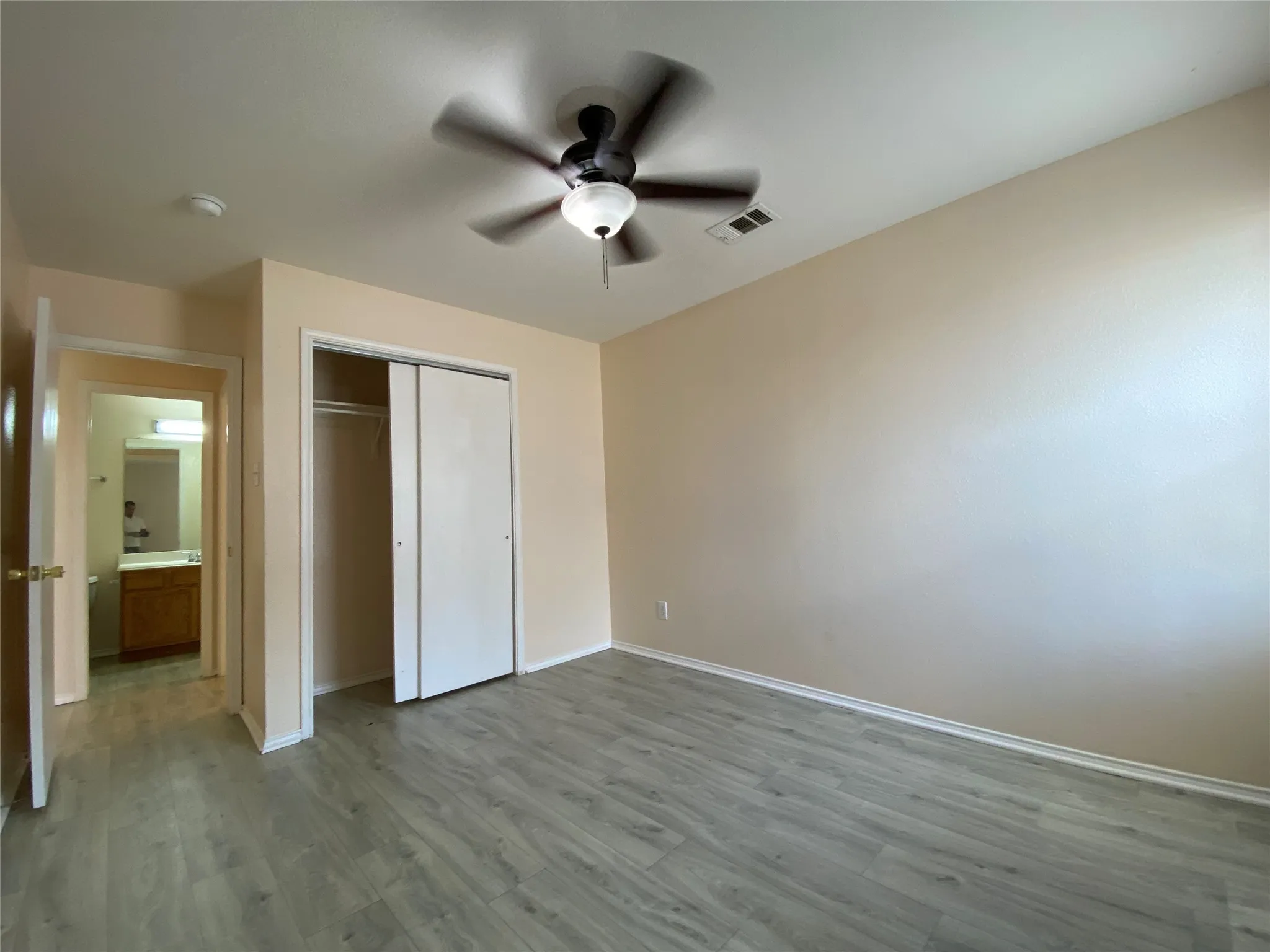 Unfurnished bedroom with a closet, a ceiling fan, wood finished floors, baseboards, and visible vents