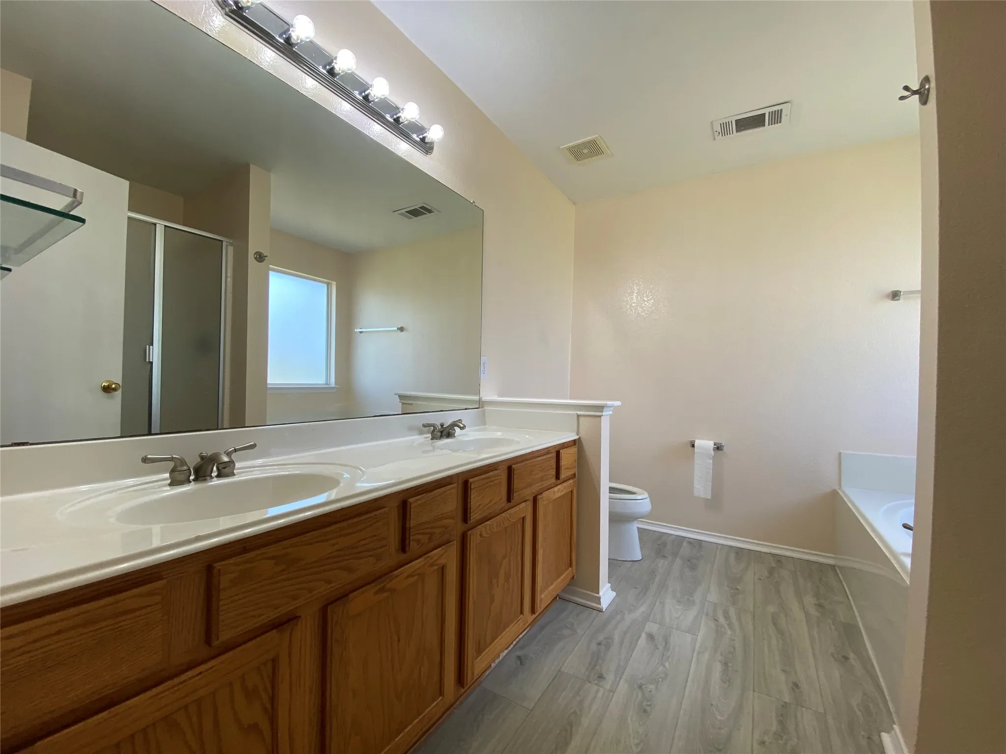 Full bath with a sink, a shower stall, and visible vents