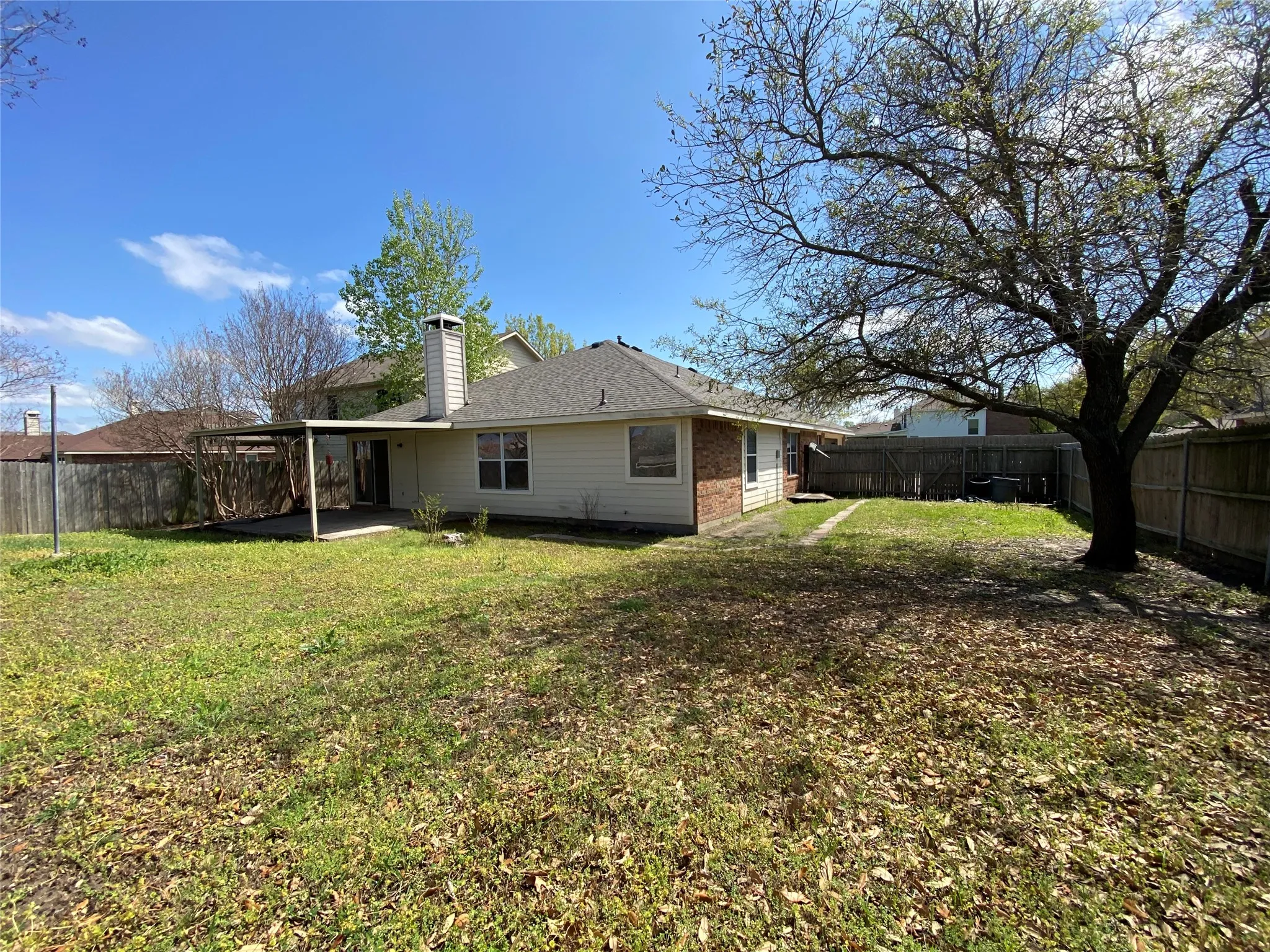 Back of property featuring an attached carport, a fenced backyard, a yard, and a patio area