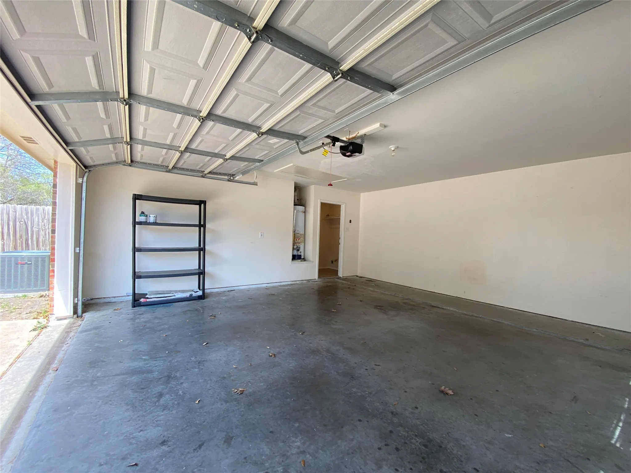 Garage featuring water heater, a garage door opener, cooling unit, and baseboards