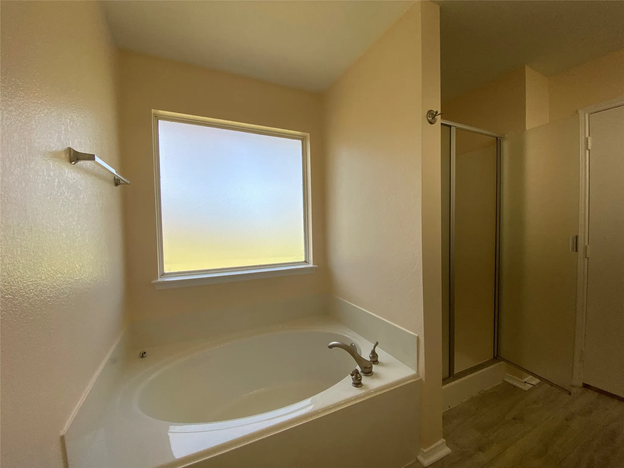 Bathroom with wood finished floors, a bath, and a shower stall