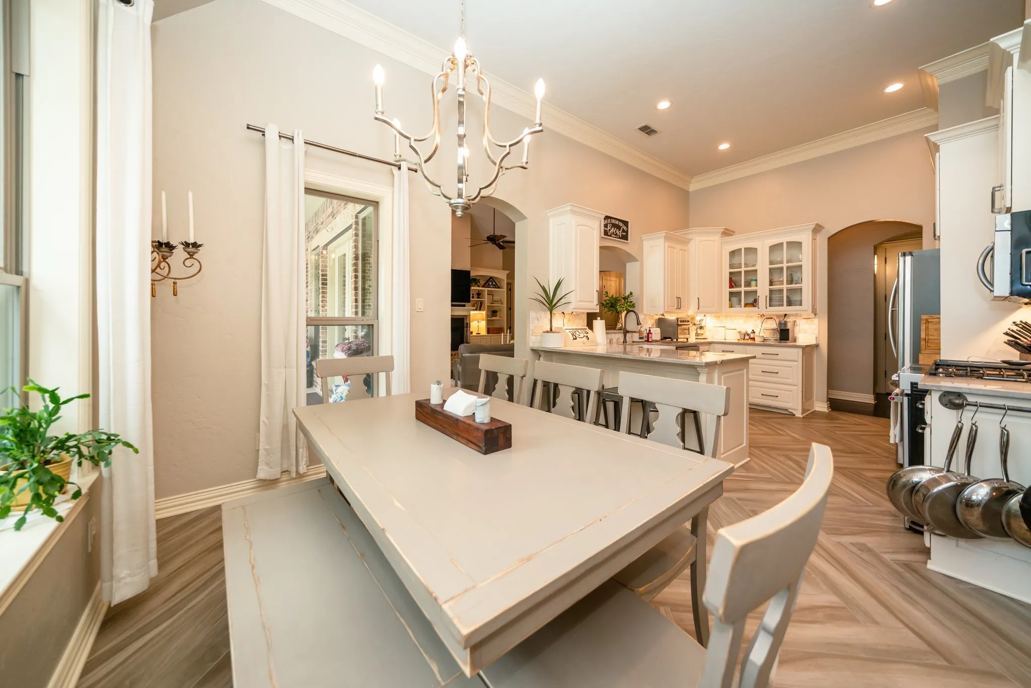 High ceilings, crown molding, arched doorways, white cabinetry, and wood-finish flooring