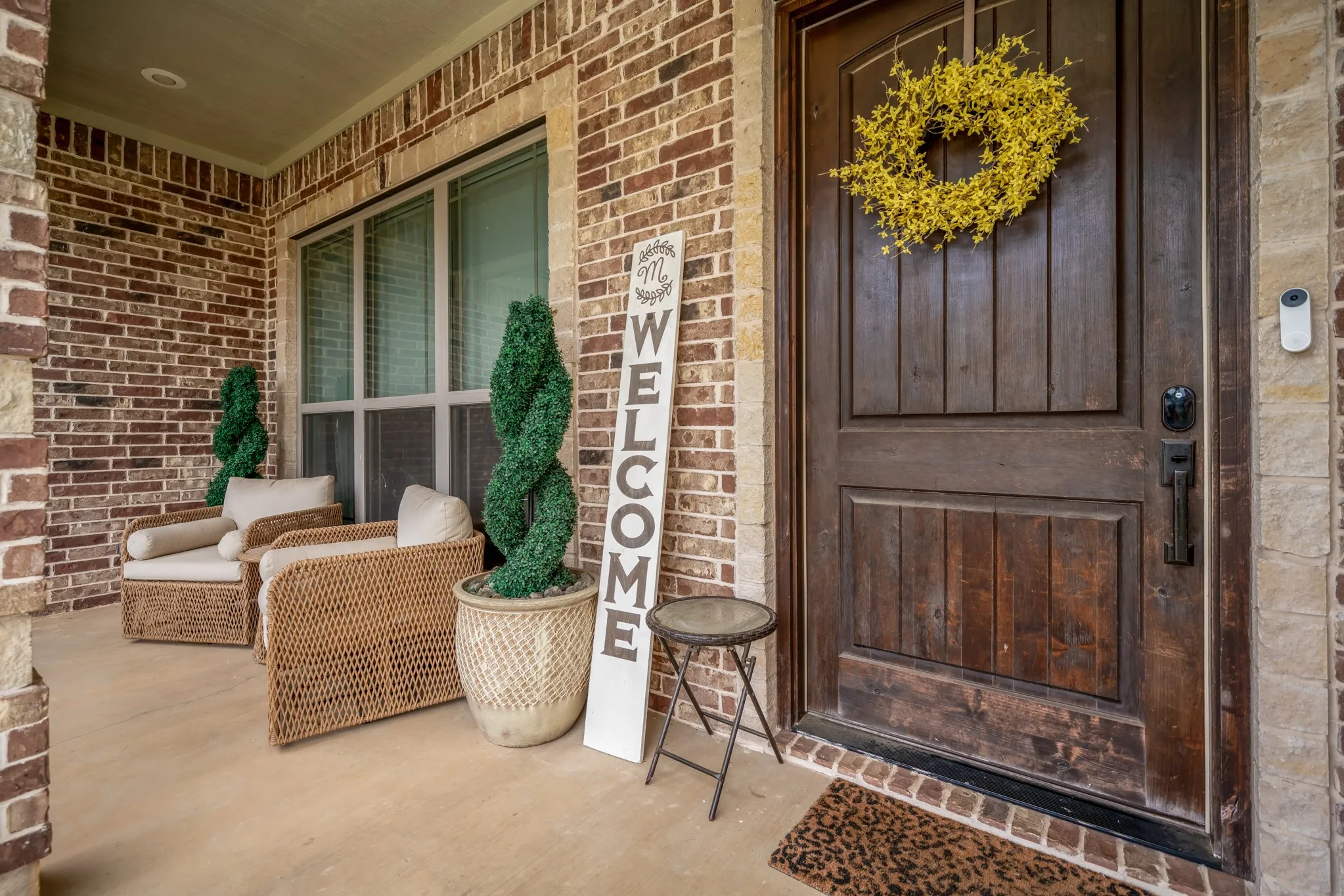 Brick exterior with stone accents, wood-finish entry door, and covered porch