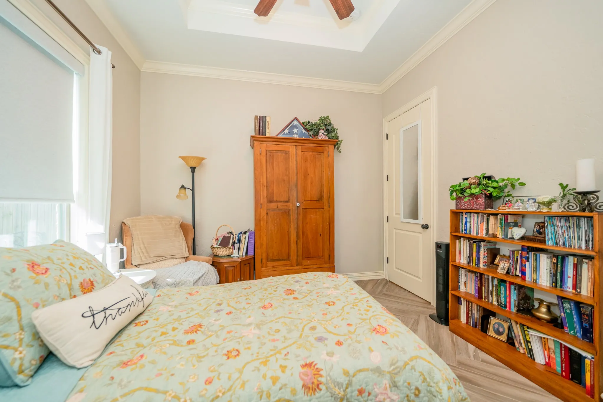 Tray ceiling with a ceiling fan, crown molding, and wood-finish flooring
