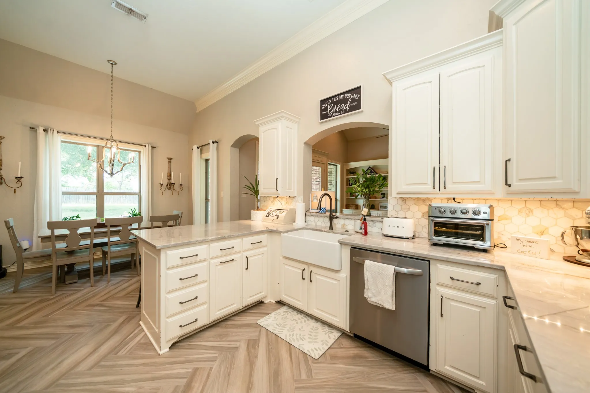 Kitchen featuring white cabinetry, a large center island with counter seating, stainless steel appliances, and wood-finish flooring