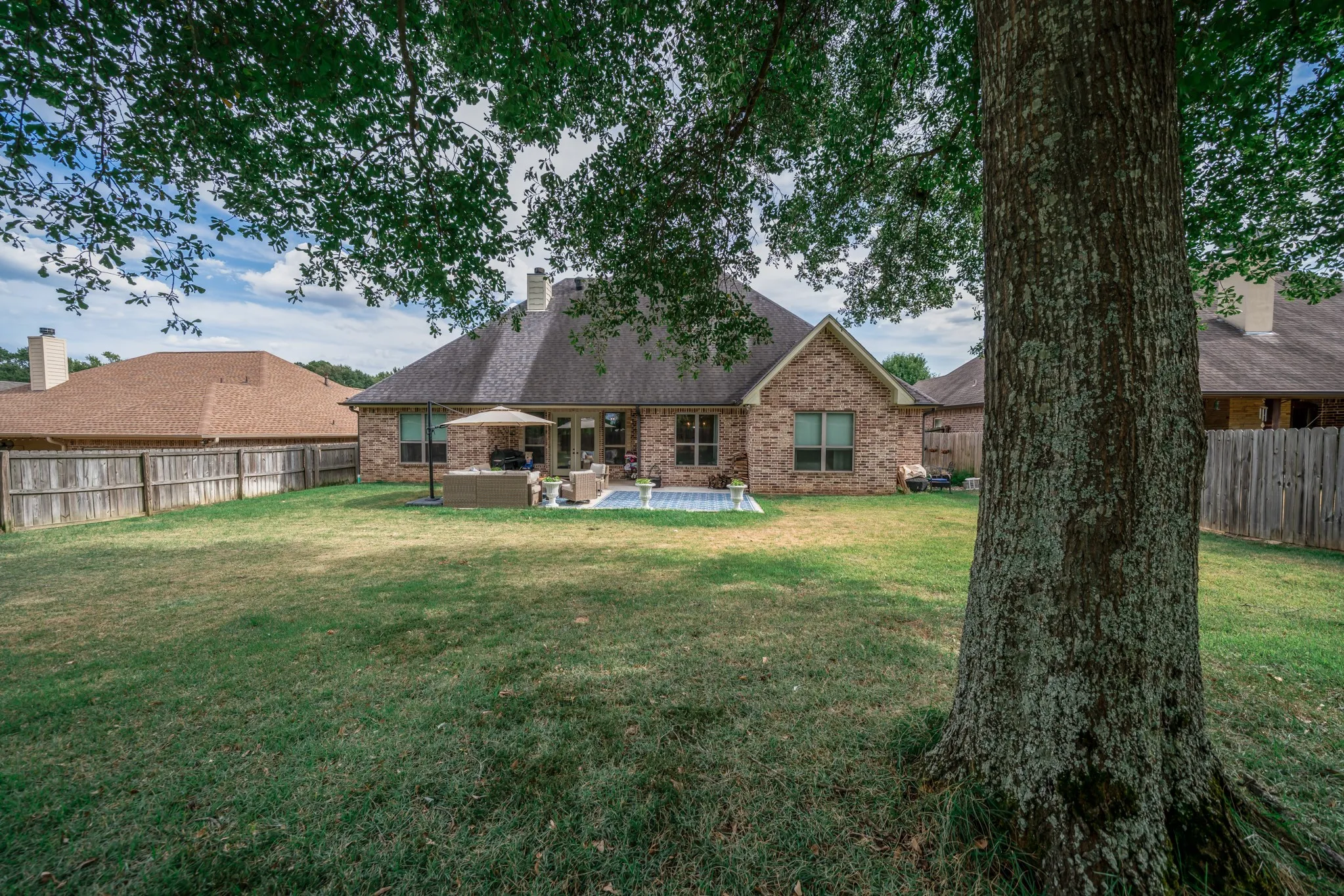 Expansive backyard featuring a brick exterior, shingle roof, and a privacy fence