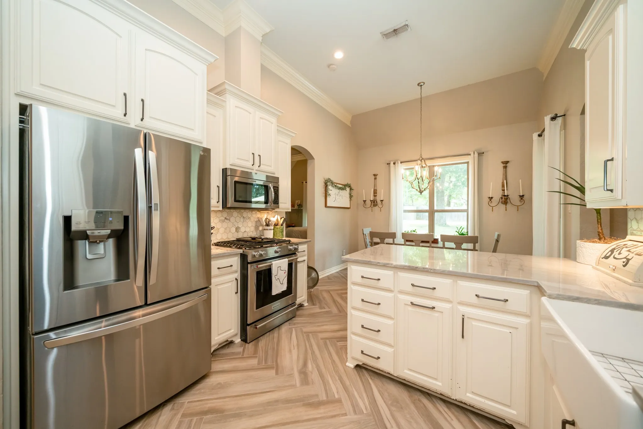 Vaulted ceiling kitchen featuring white cabinetry, stainless steel appliances, a center island with countertop, and wood-finish flooring