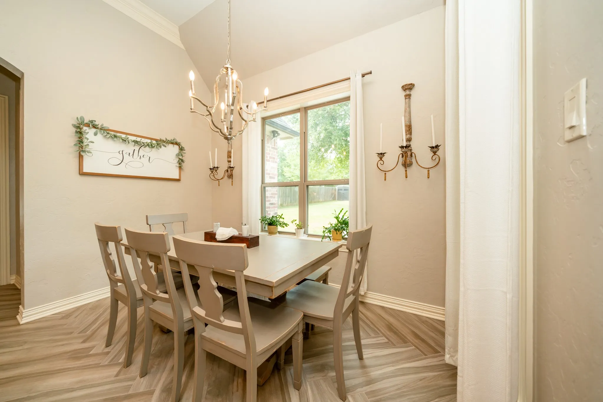 Elegant dining room featuring a wood-finish table with seating for four, hardwood flooring throughout, and abundant natural light from a large multi-pane window