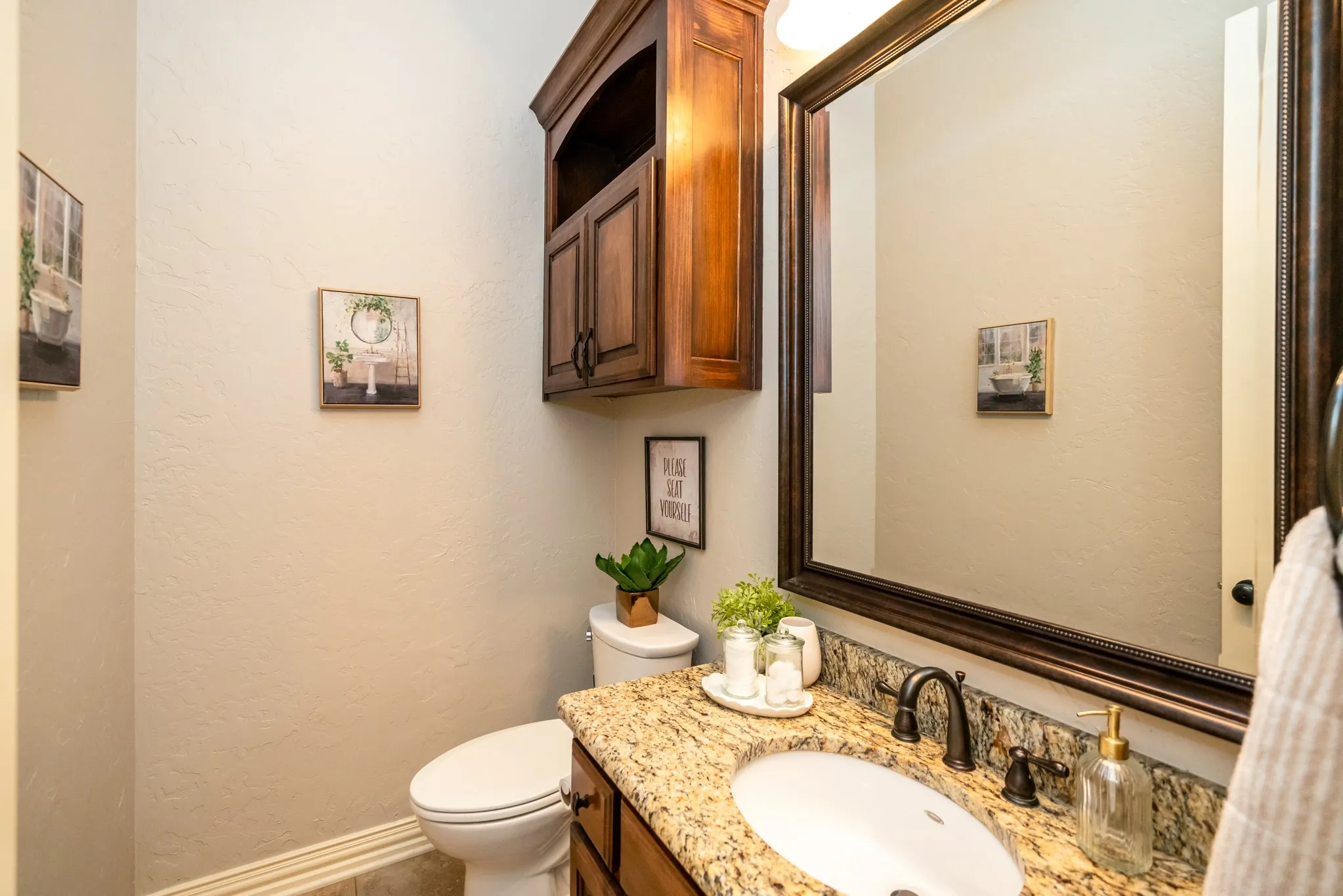 Bathroom with a white toilet, a wood-finish vanity, and a granite-style countertop with an undermount sink
