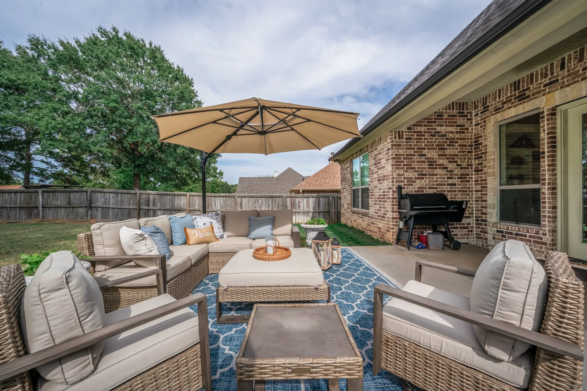 Outdoor patio featuring a concrete surface, a brick exterior wall, and a wood privacy fence