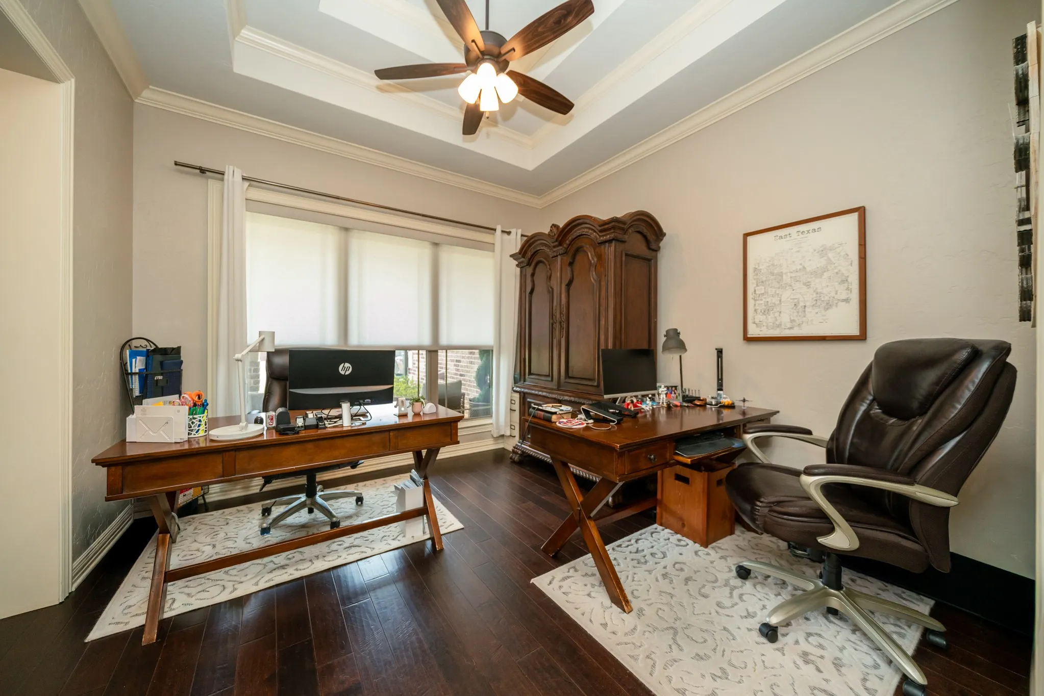 Tray ceiling with a ceiling fan, dark wood-finish flooring, and crown molding