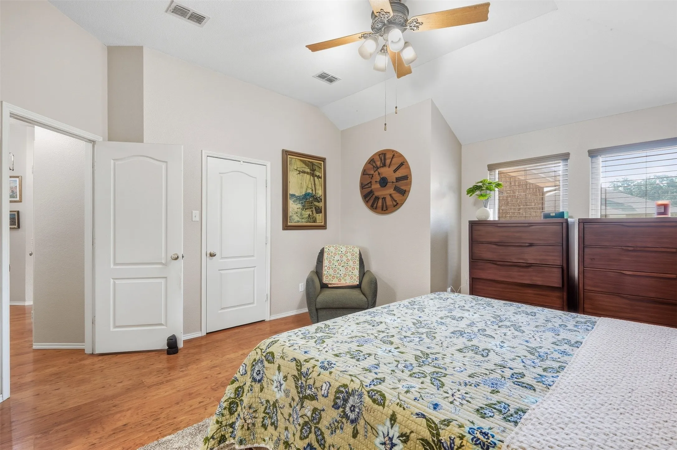 Vaulted ceiling with a ceiling fan, wood-finish flooring, and white interior doors with arched panels