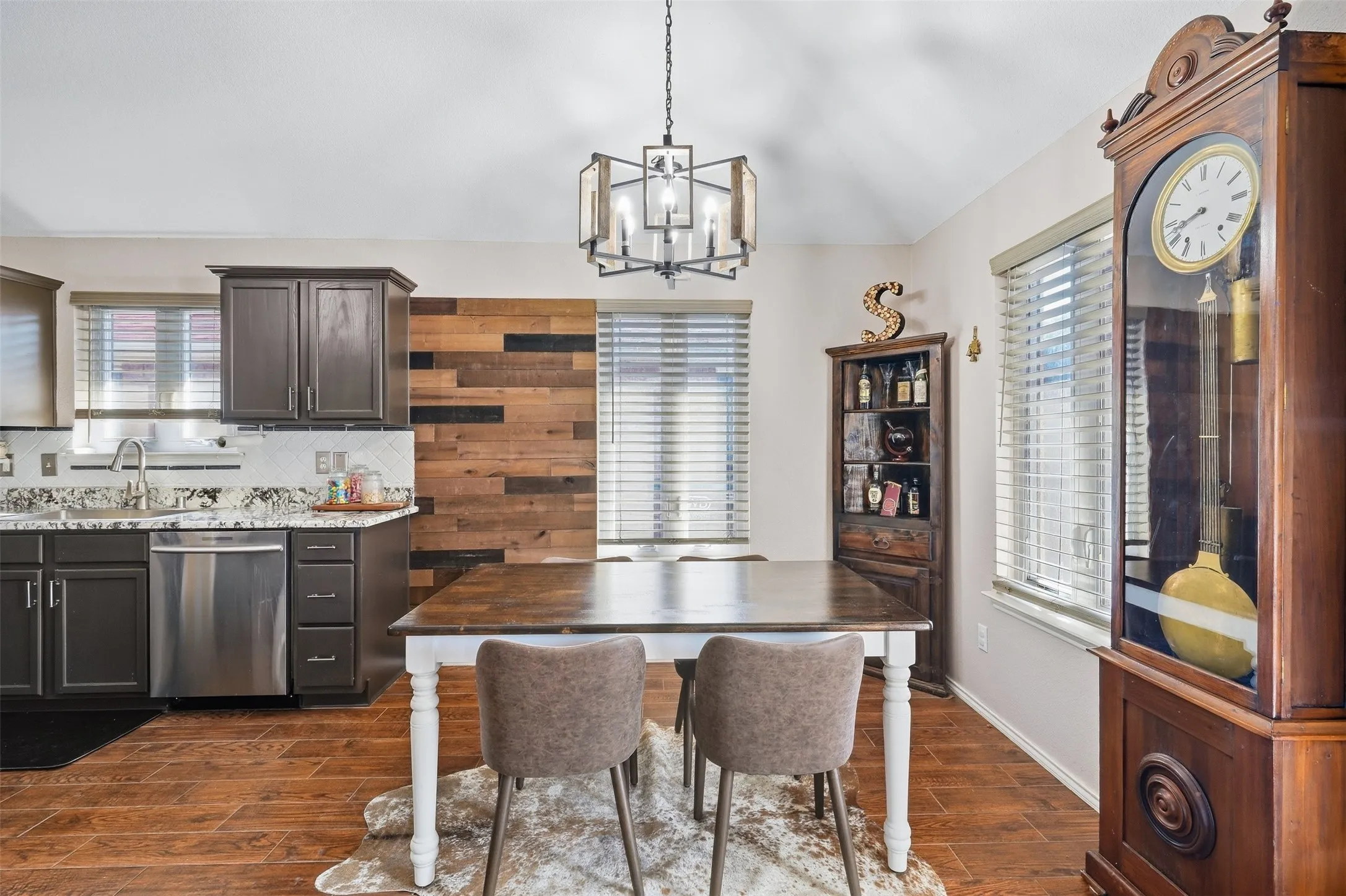 Kitchen and dining area featuring wood-finish flooring, dark wood cabinetry, light countertops, and a decorative wood-paneled accent wall