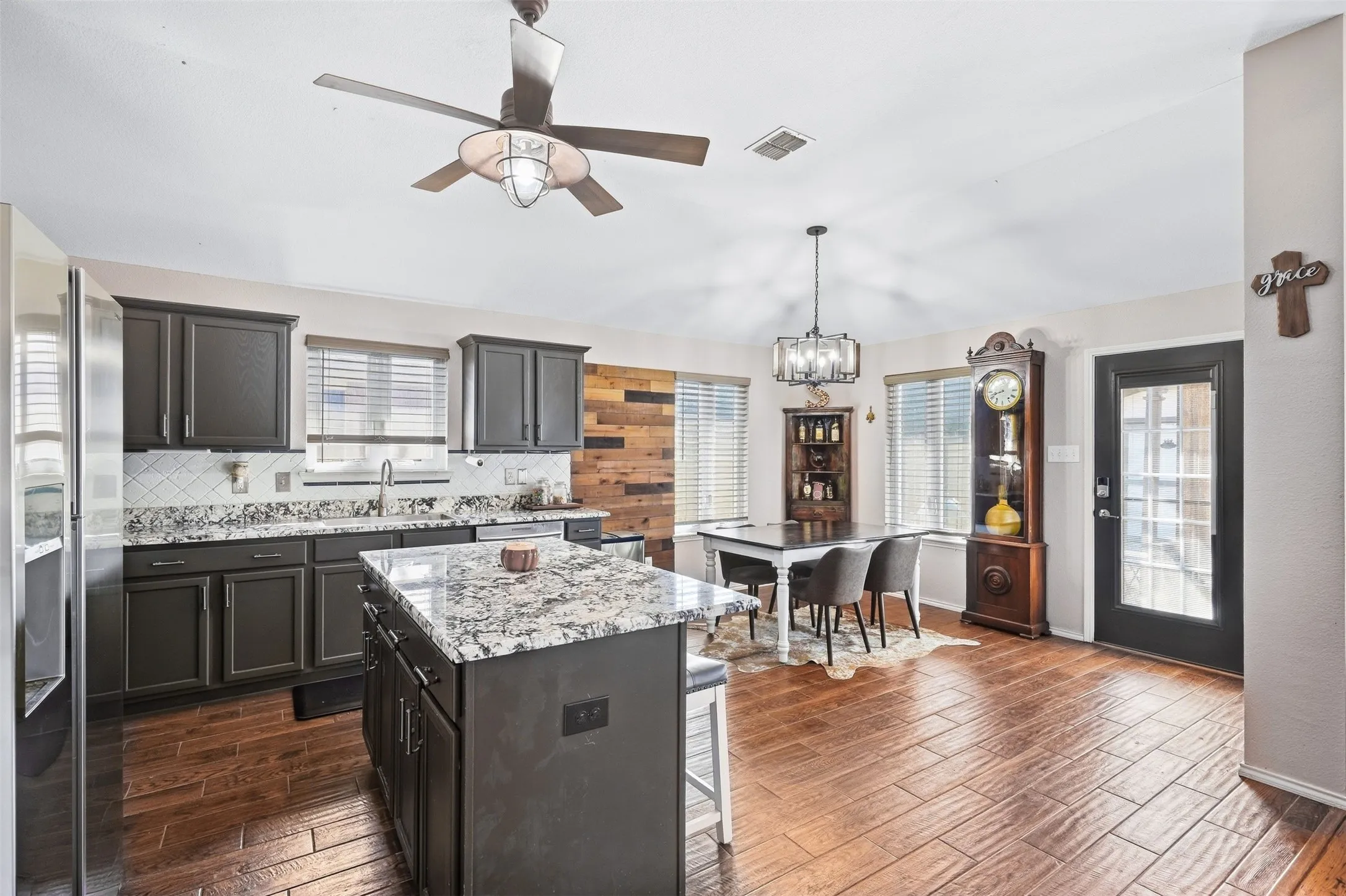 Wood-finish flooring, dark cabinetry, and white countertops with a patterned finish