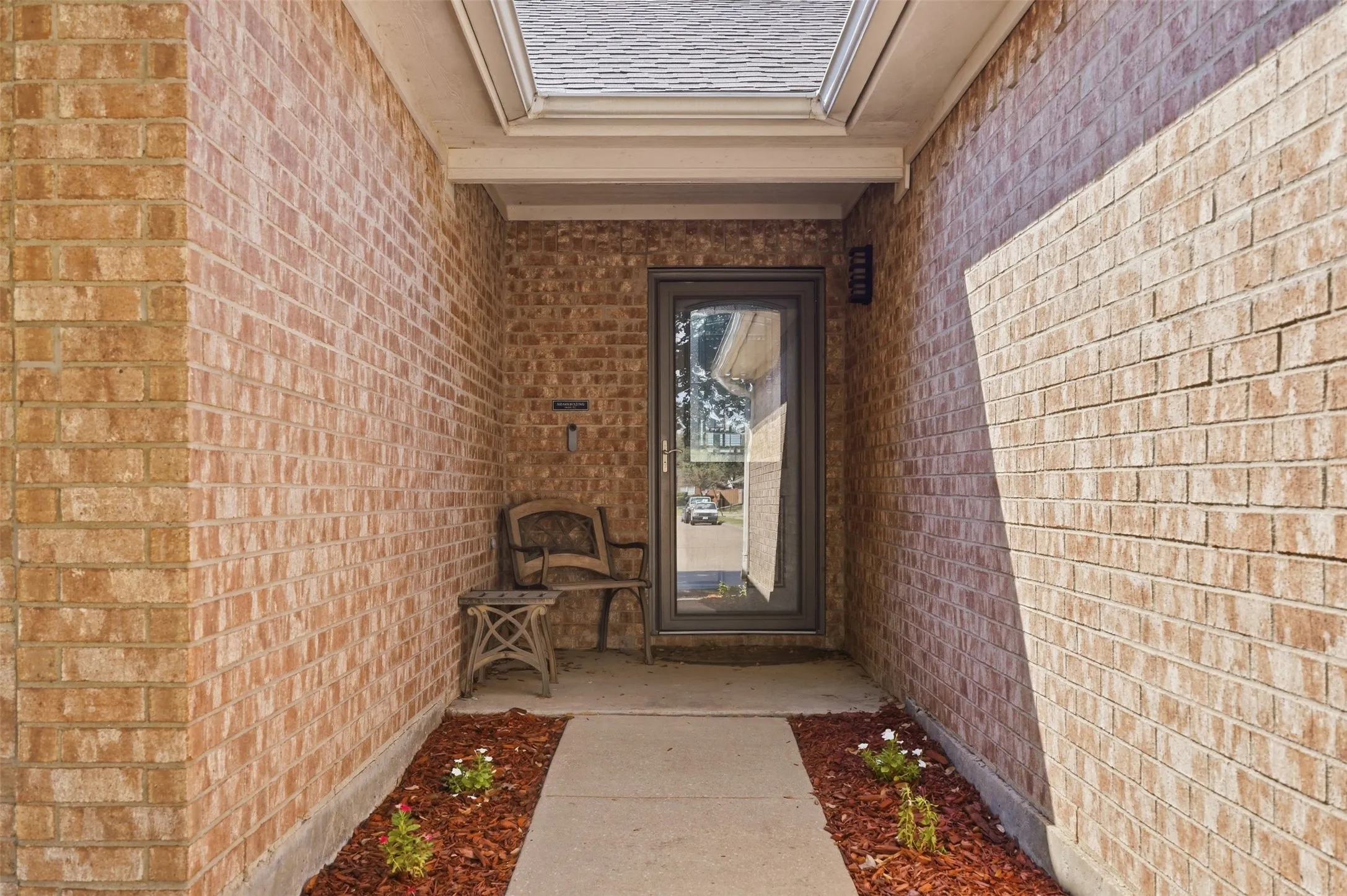 Brick exterior facade featuring a recessed entry, full-lite glass door, and a covered porch