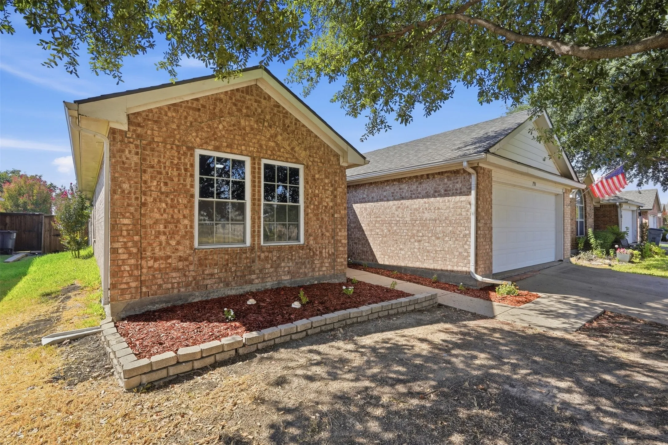 Brick exterior with a prominent mature tree and a concrete driveway