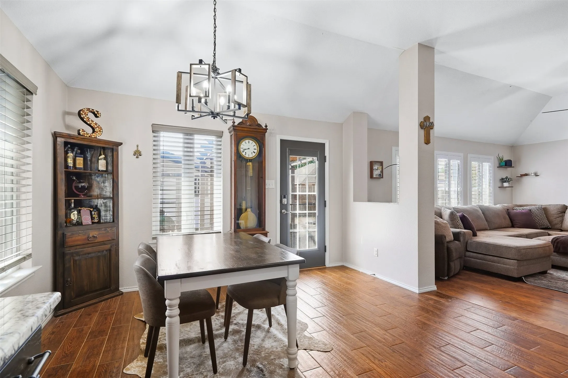 Vaulted ceiling, wood-finish flooring, contemporary chandelier, paneled glass door, and a half-wall partition